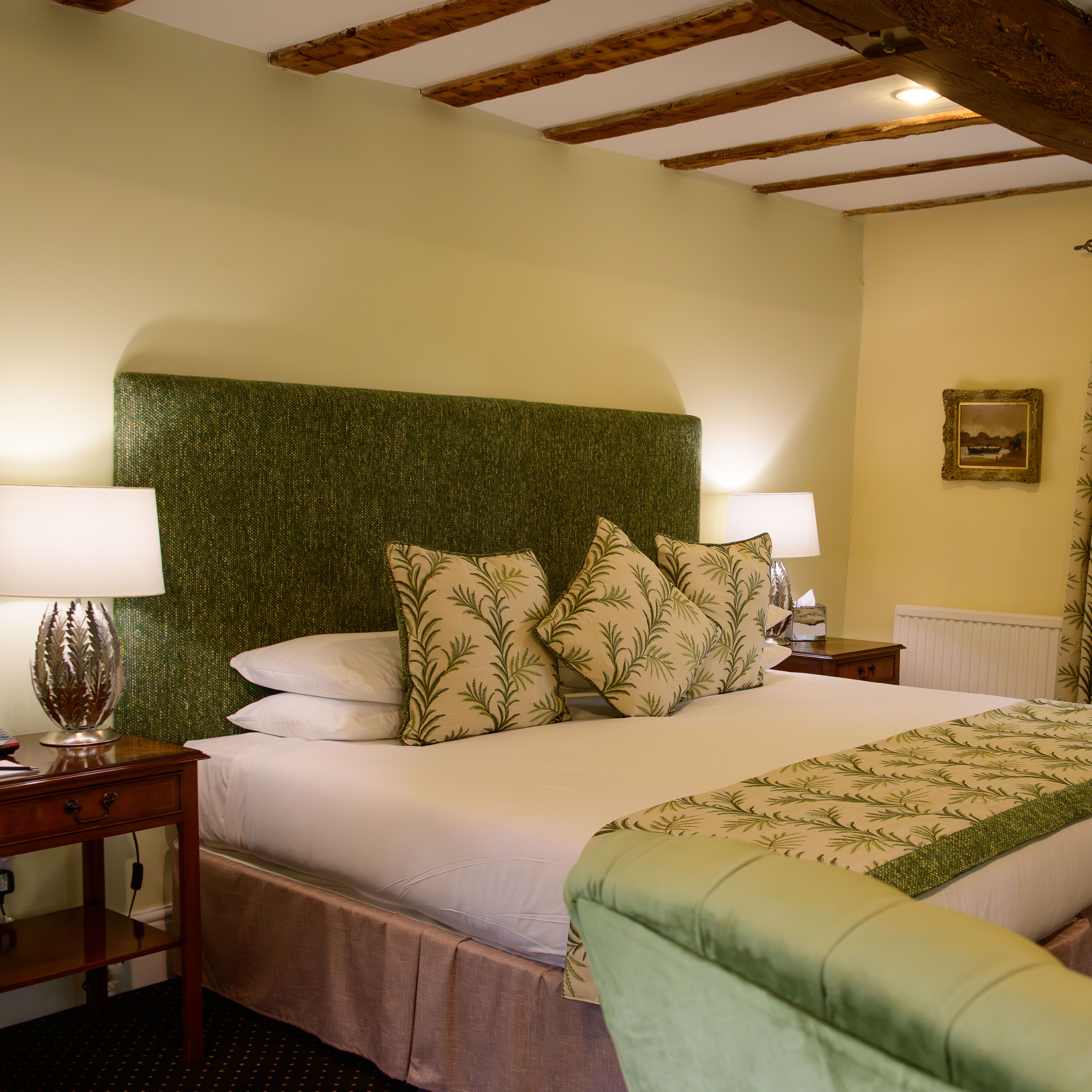 Cozy hotel room with a large bed, green accents, and a window with a garden view