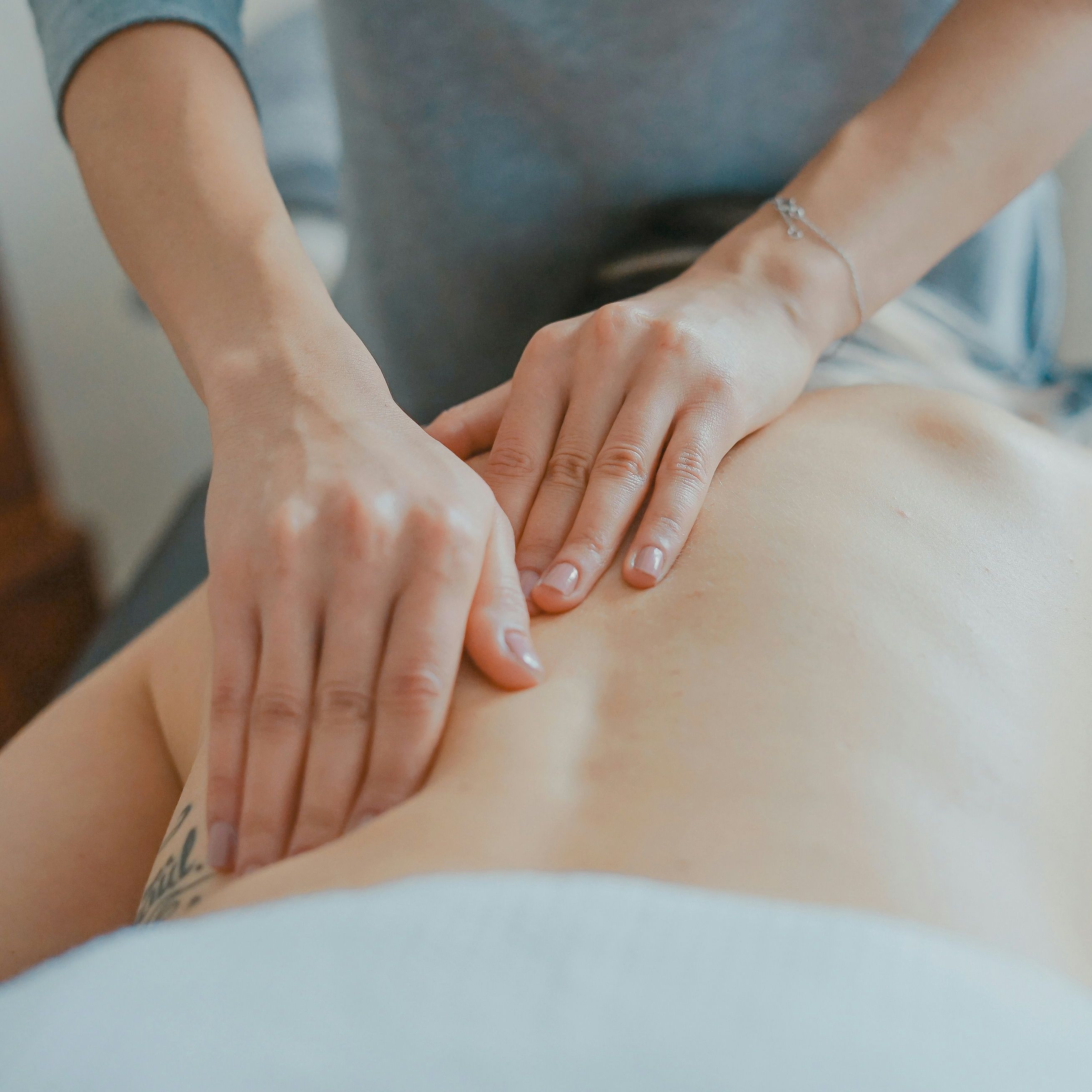 Person receiving a back massage from a professional masseuse.
