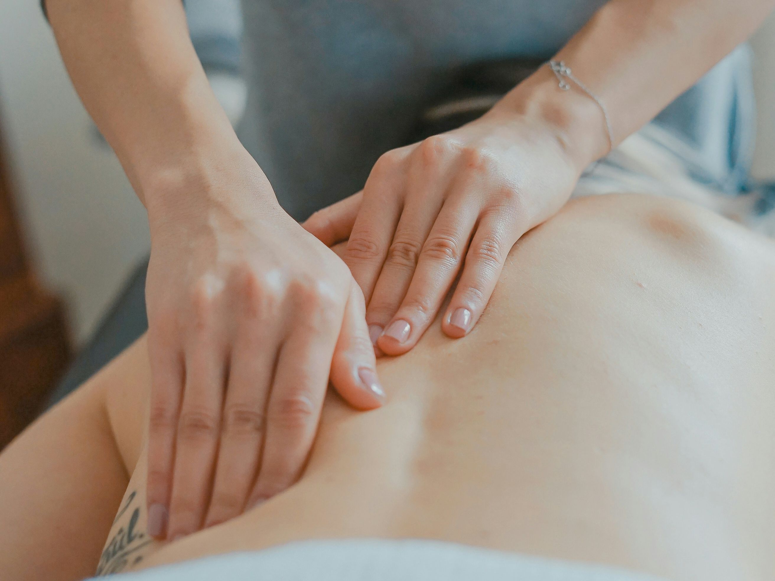 Person receiving a back massage from a professional masseuse.