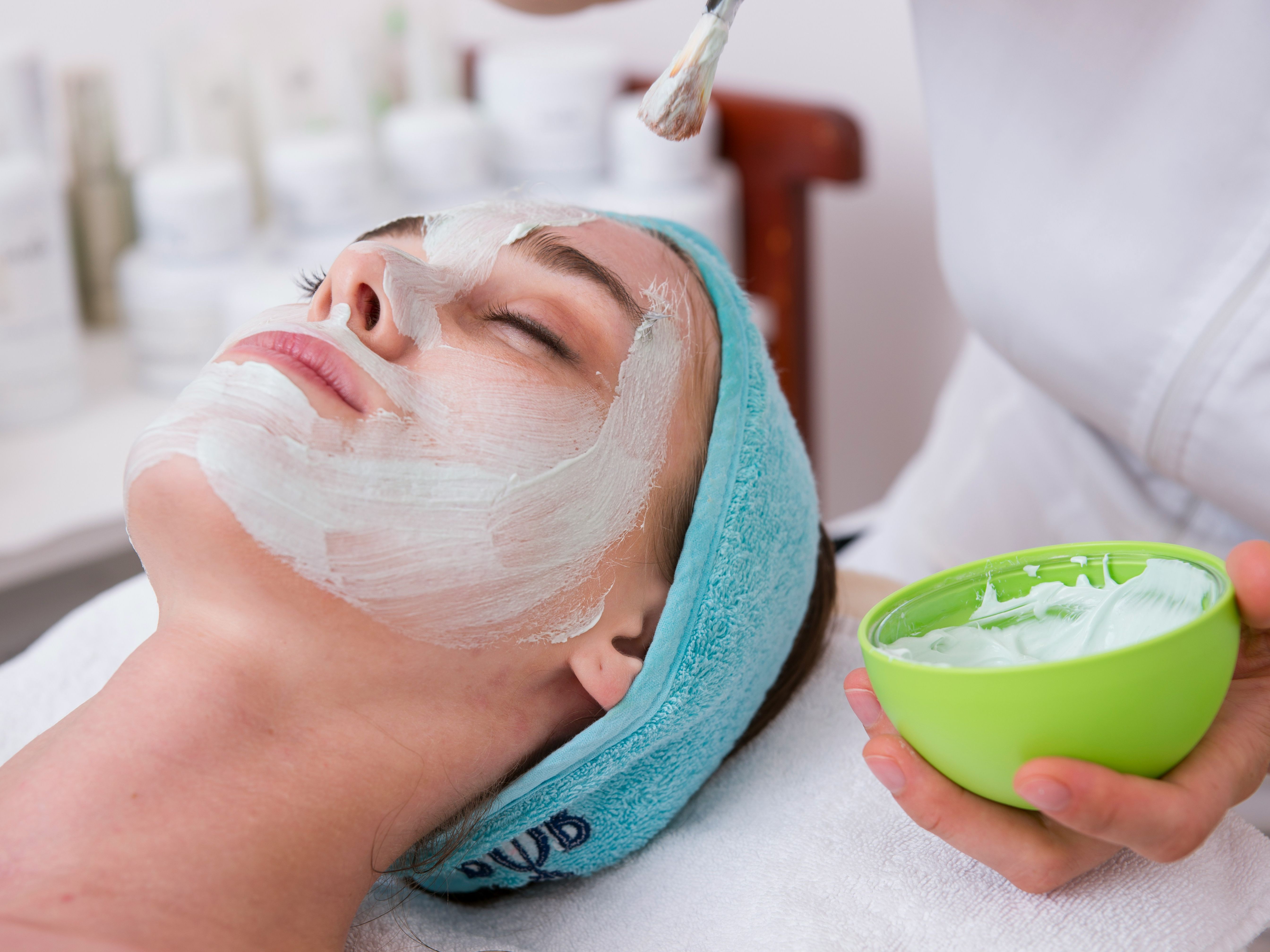 Person receiving a facial treatment with a white mask applied to their face.