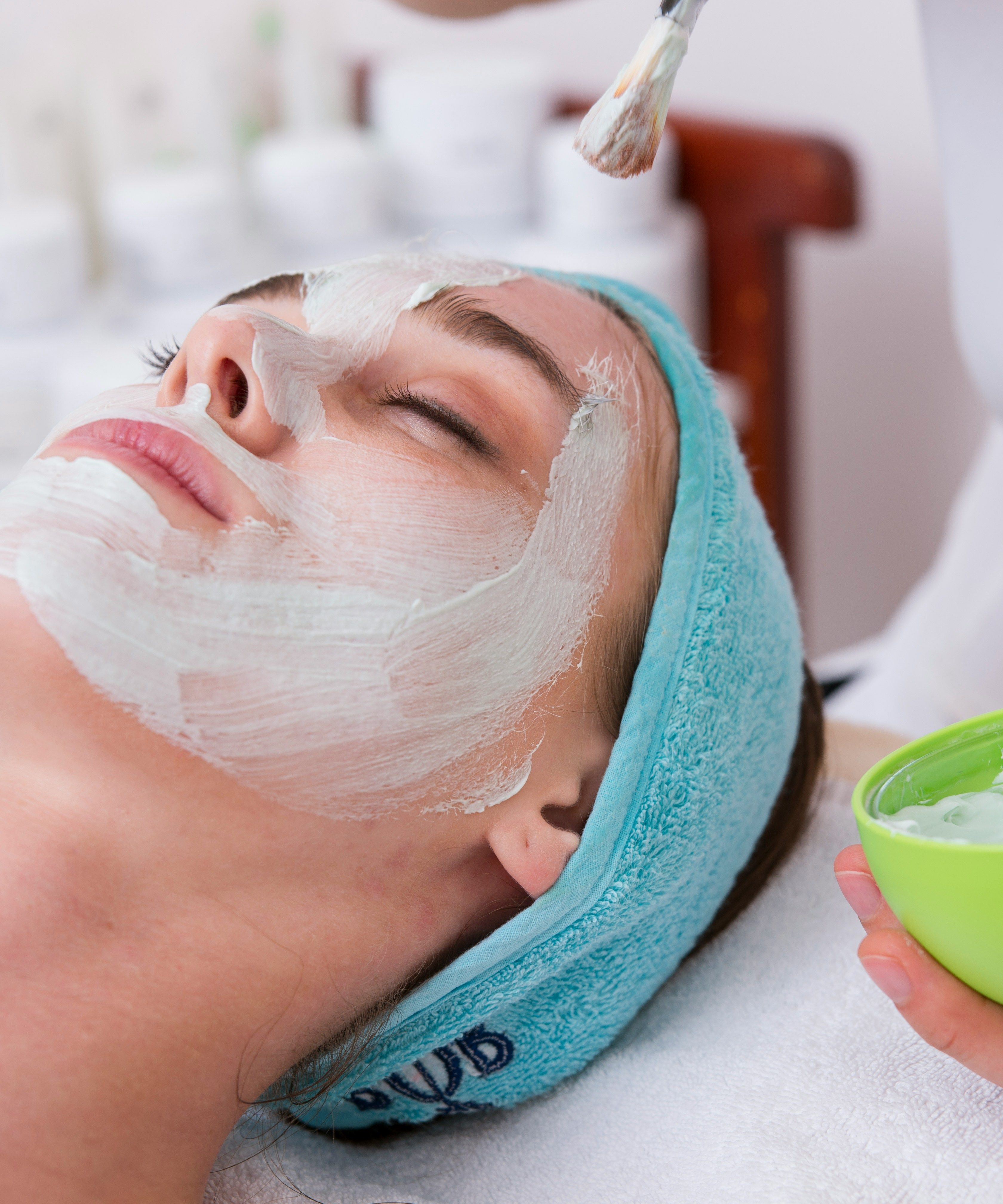 Person receiving a facial treatment with a white mask applied to their face.