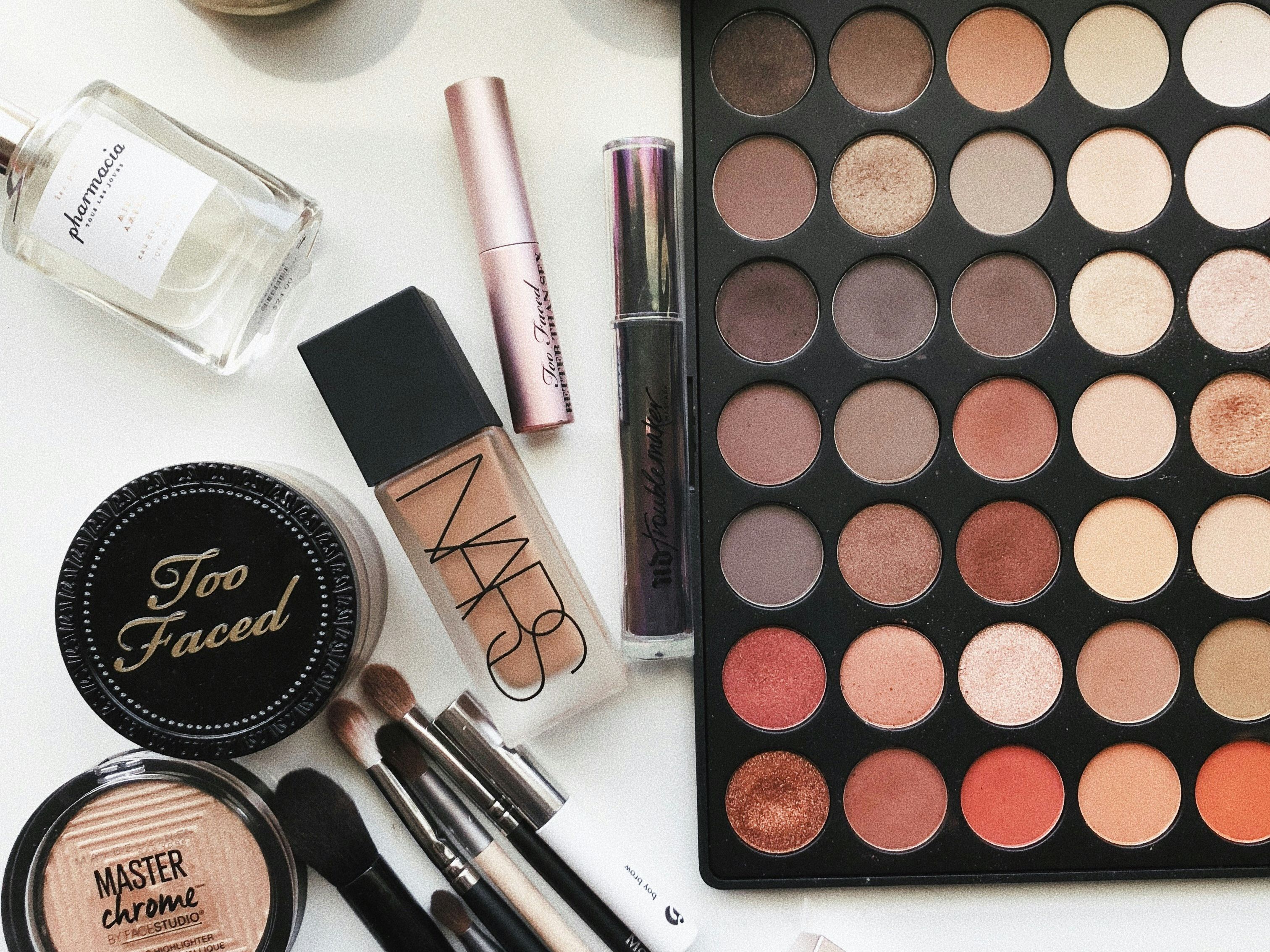 Assorted makeup products and beauty tools laid out on a white surface.