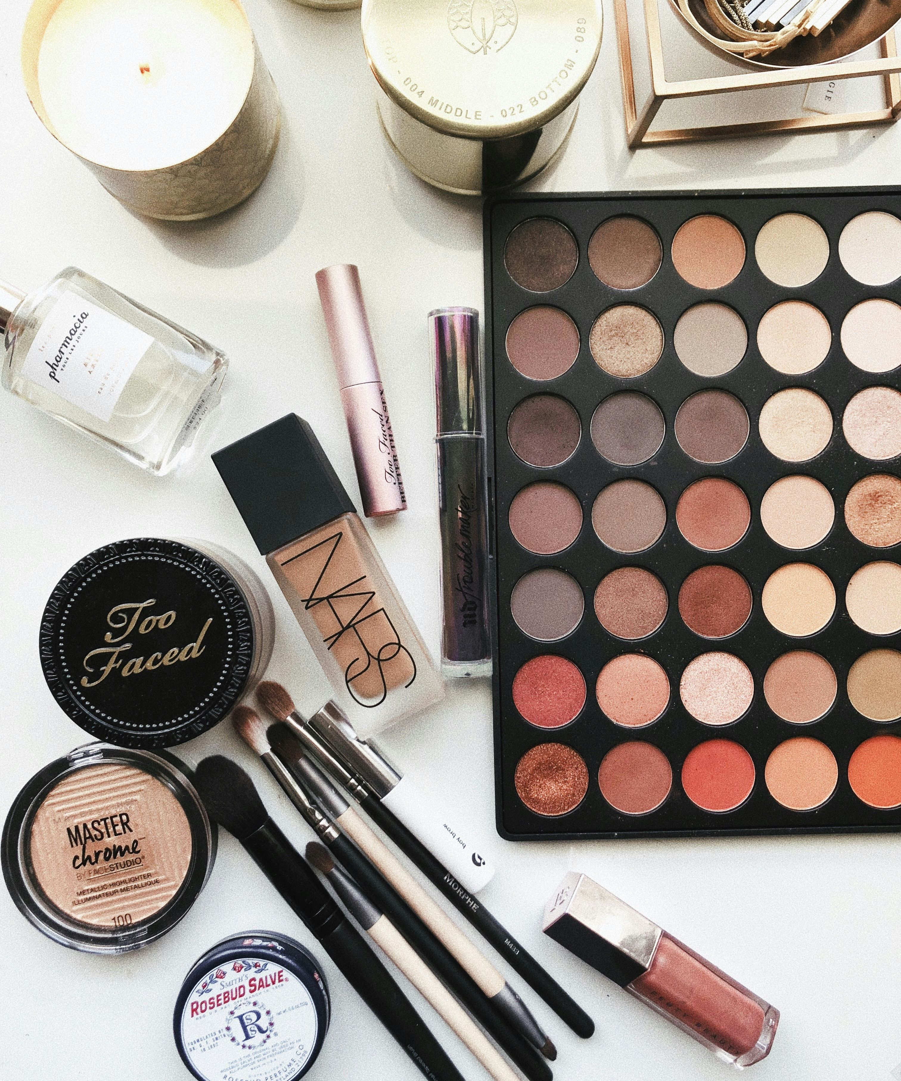 Assorted makeup products and beauty tools laid out on a white surface.