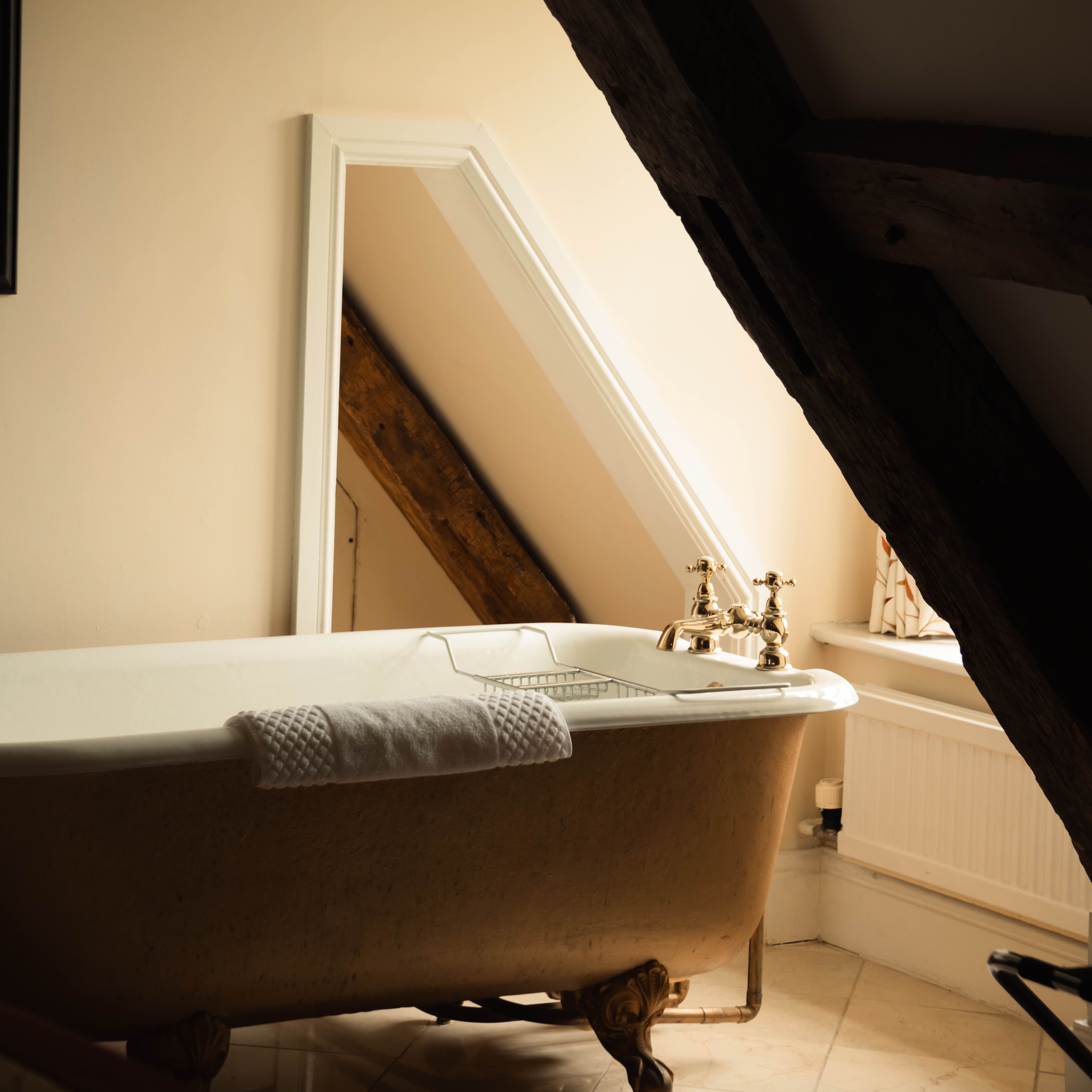 Vintage bathtub under slanted ceiling with a towel draped over the edge