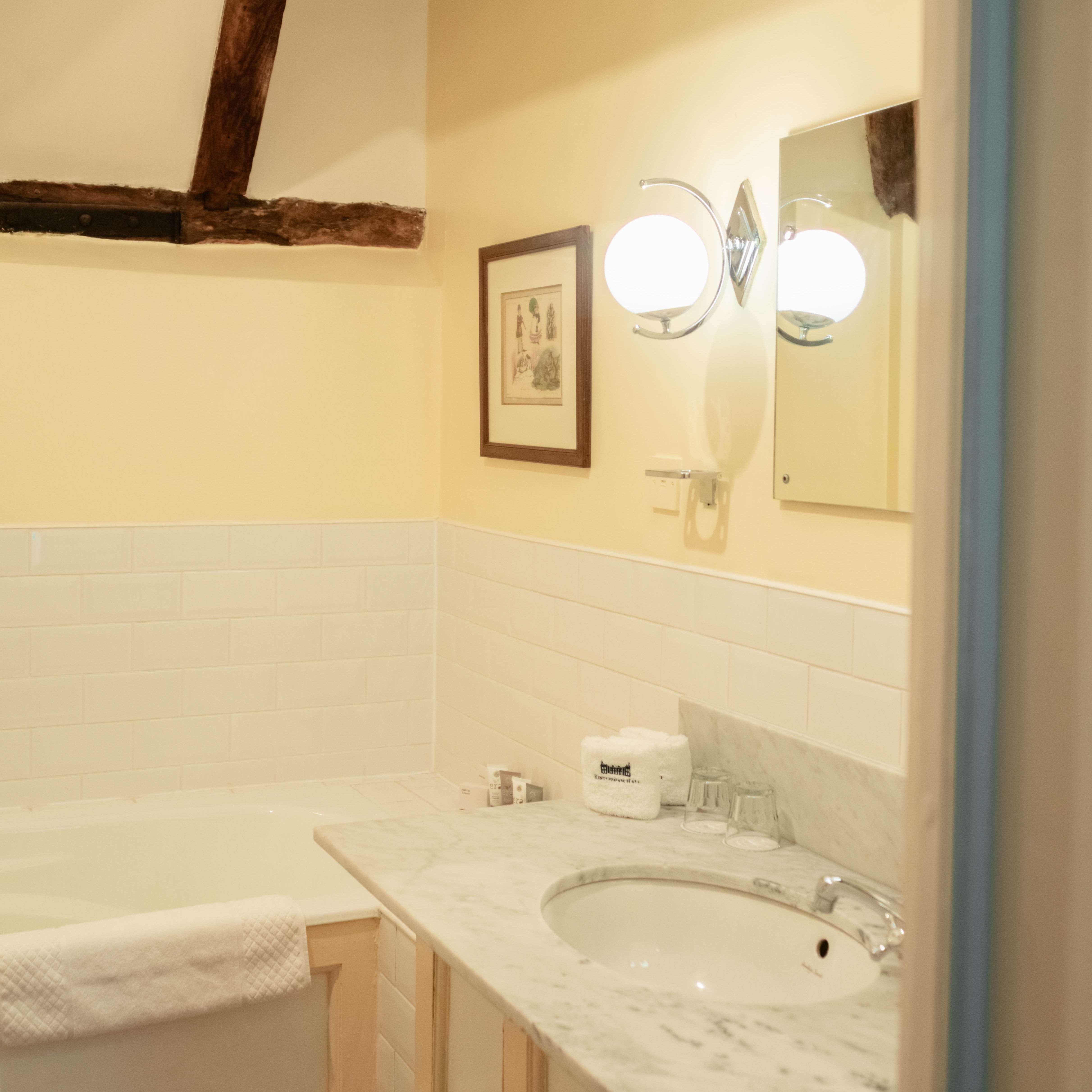 Rustic bathroom with exposed wooden beams, marble sink countertop, and bathtub