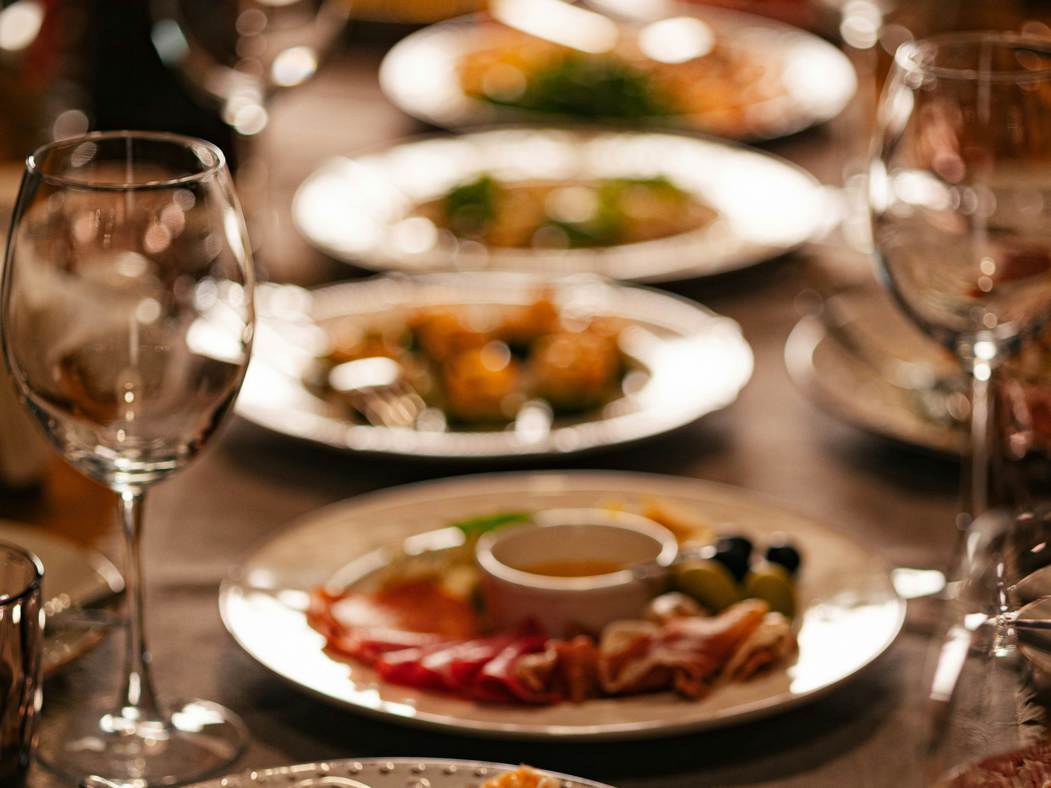 Elegant table setting with assorted plates of gourmet food and empty wine glasses