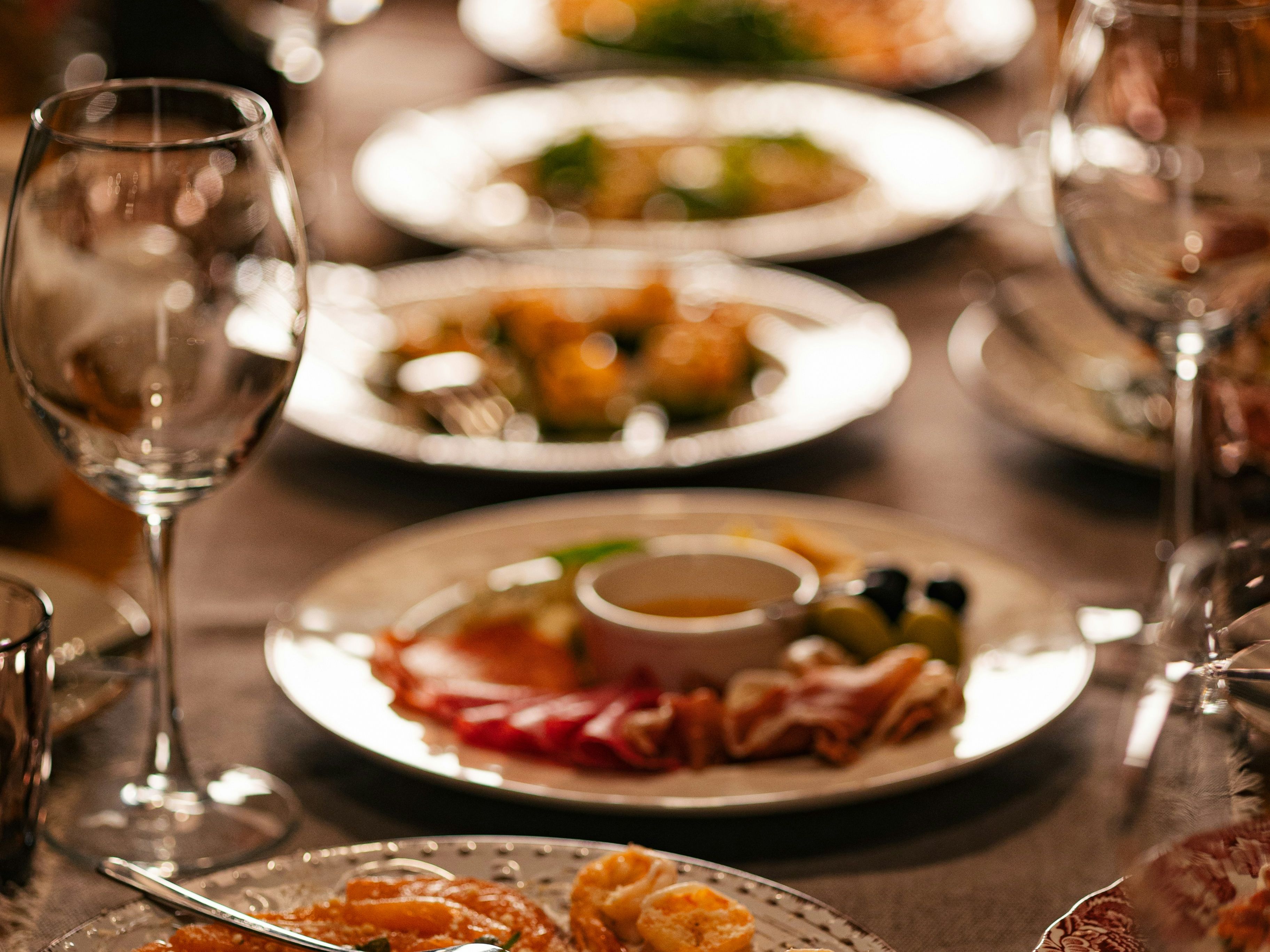 Elegant table setting with assorted plates of gourmet food and empty wine glasses