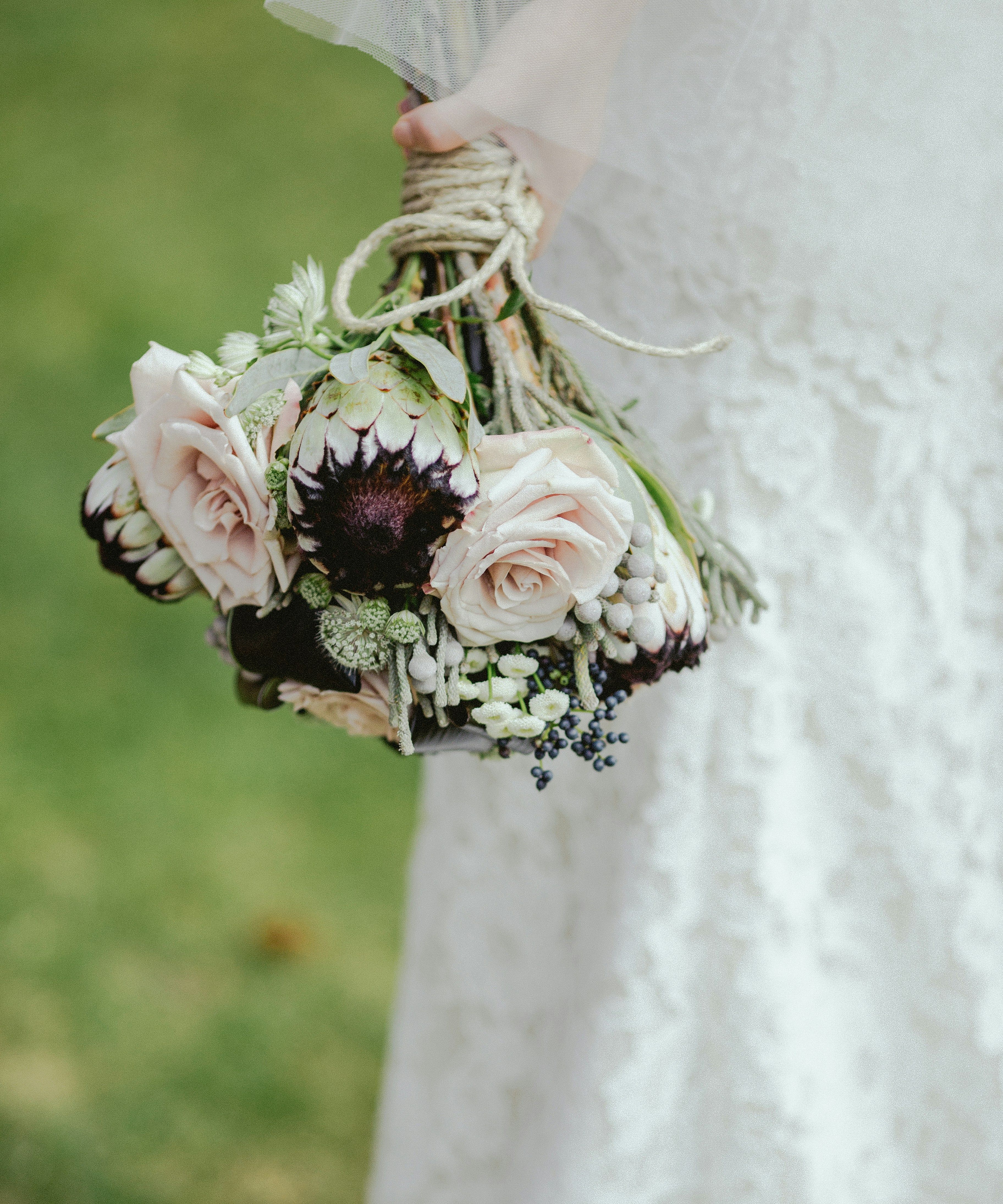 Bride holding a bouquet of pale pink roses and protea flowers