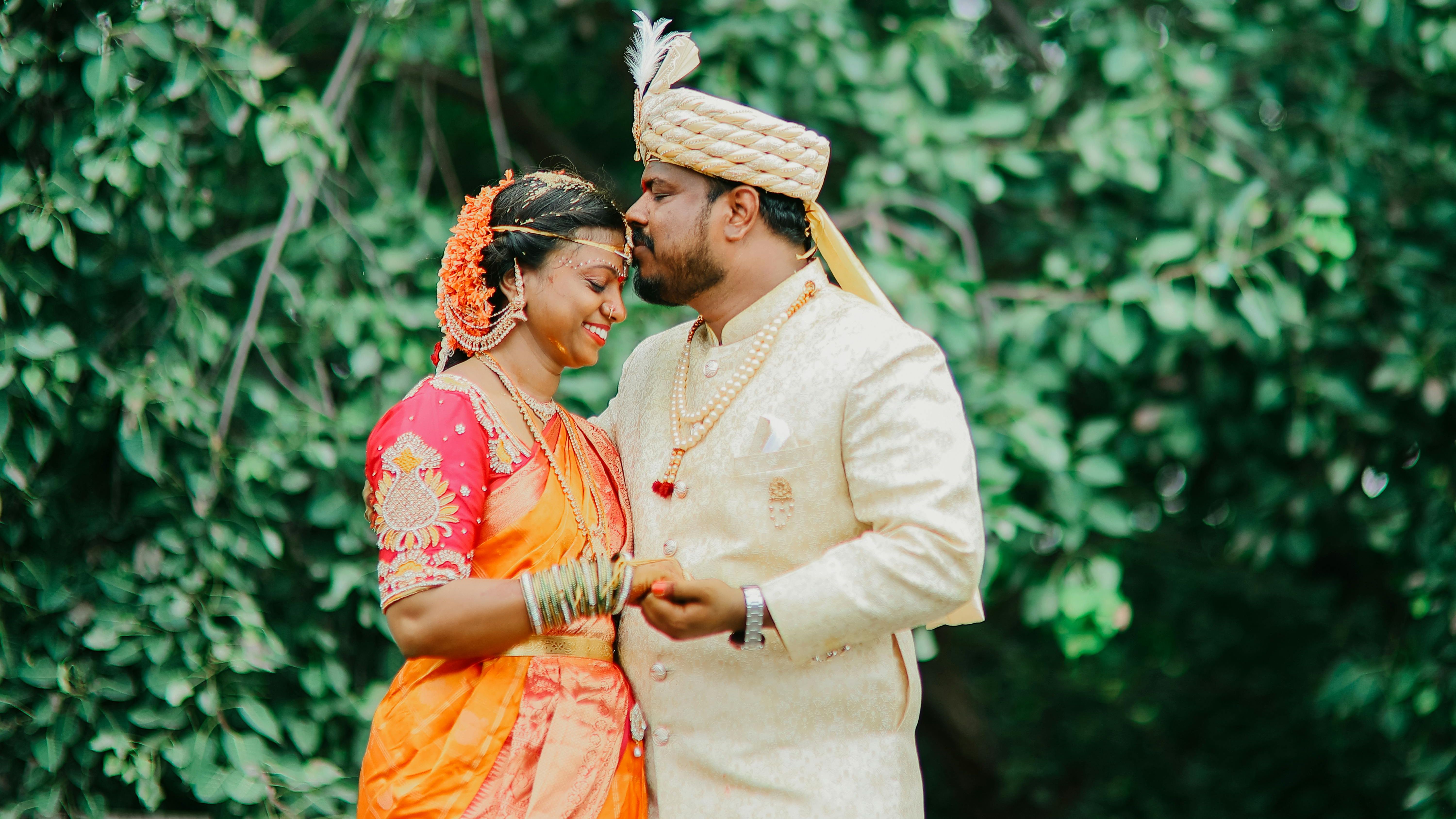 Traditional Indian bride and groom in wedding attire sharing a tender moment outdoors