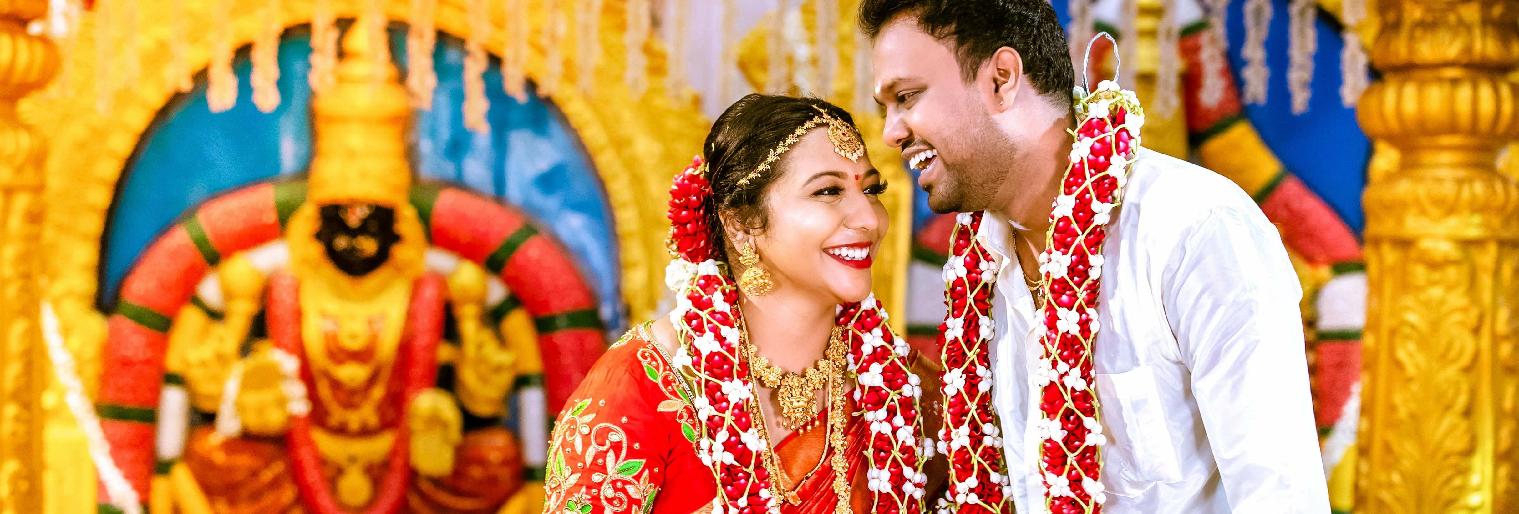 Traditional South Indian wedding couple smiling and adorned with flower garlands