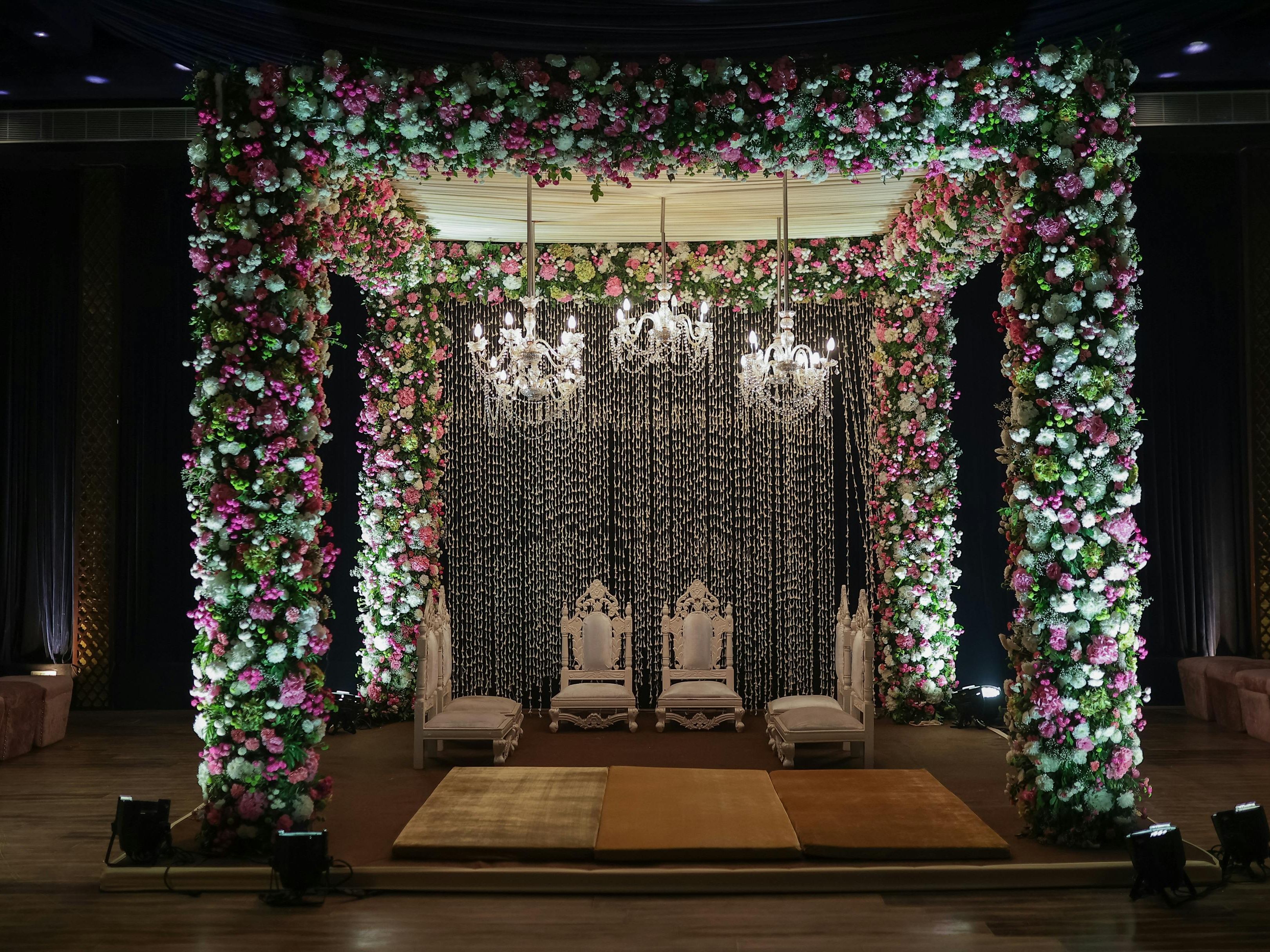 Beautifully decorated wedding mandap with floral arrangements and chandeliers