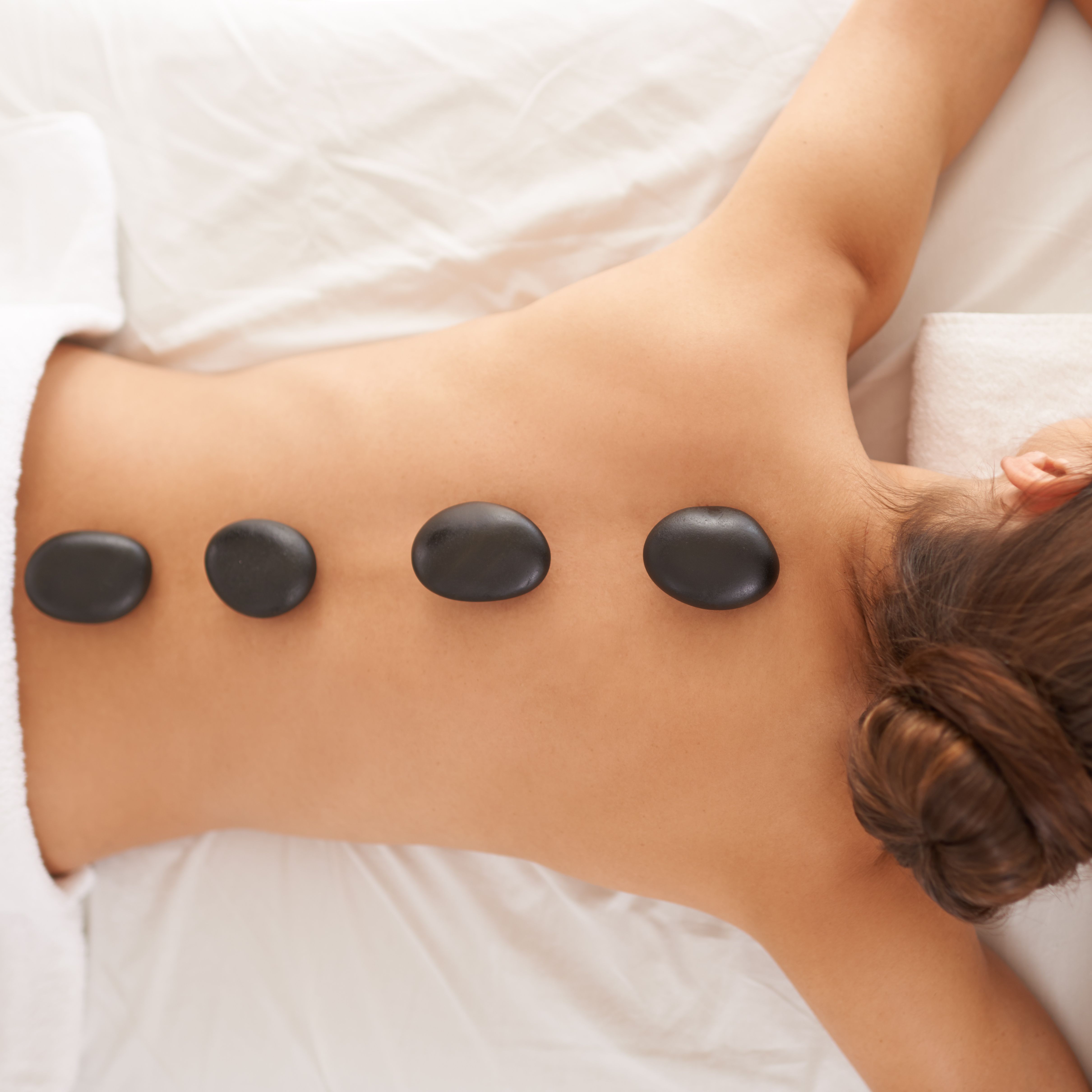 Woman receiving a hot stone massage with stones placed along her back