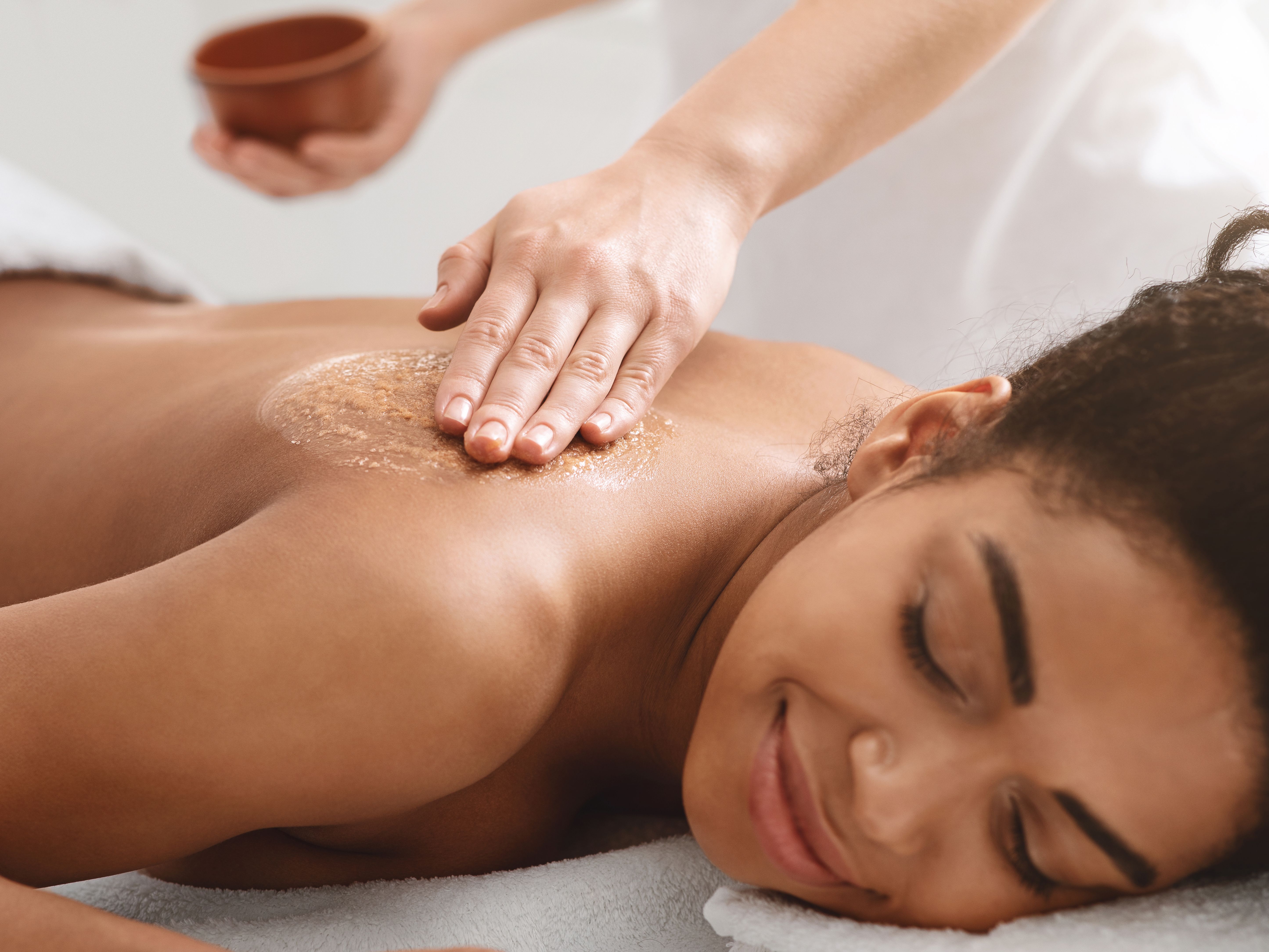 Woman receiving a relaxing back exfoliation treatment at a spa