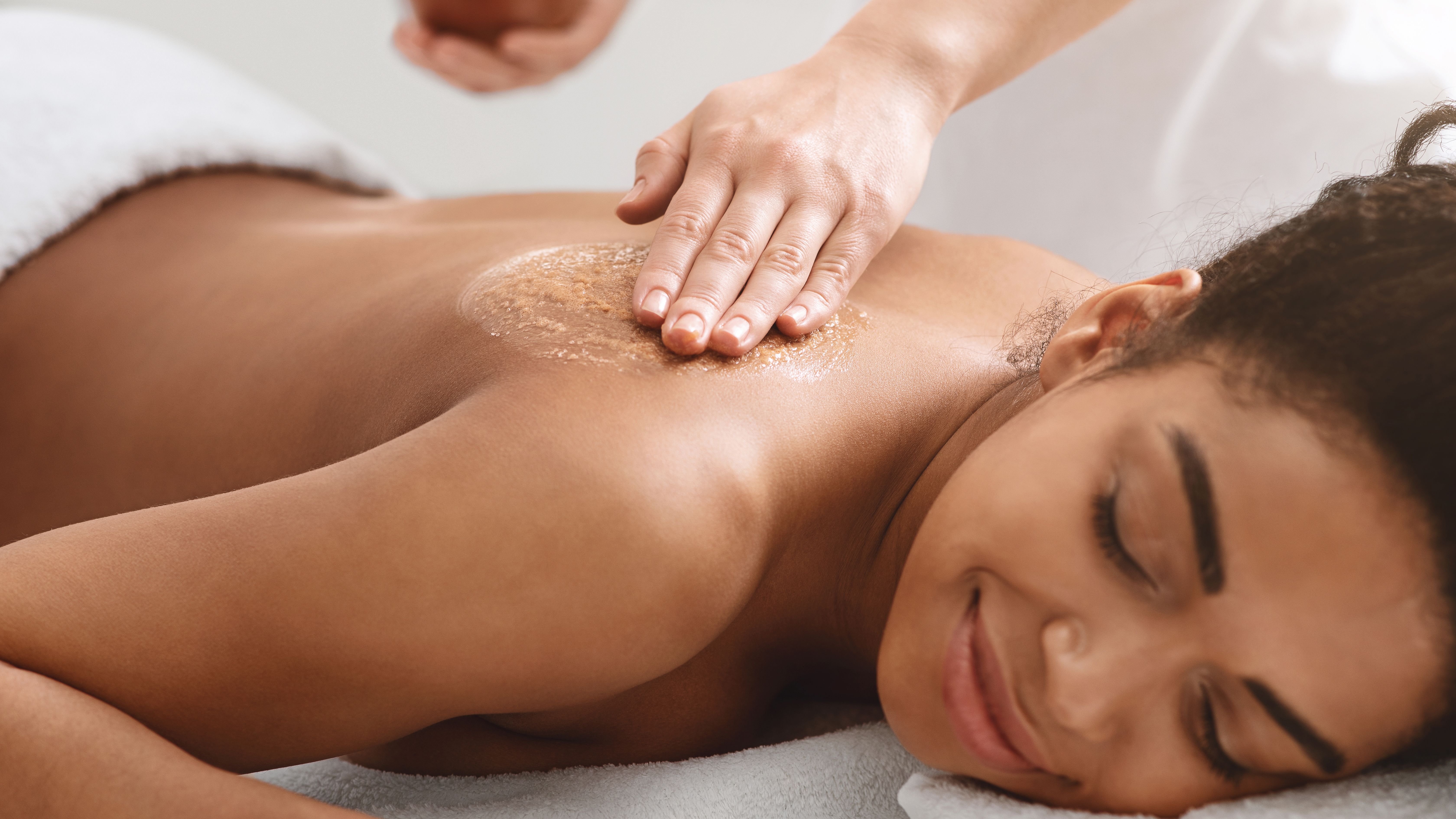 Woman receiving a relaxing back exfoliation treatment at a spa