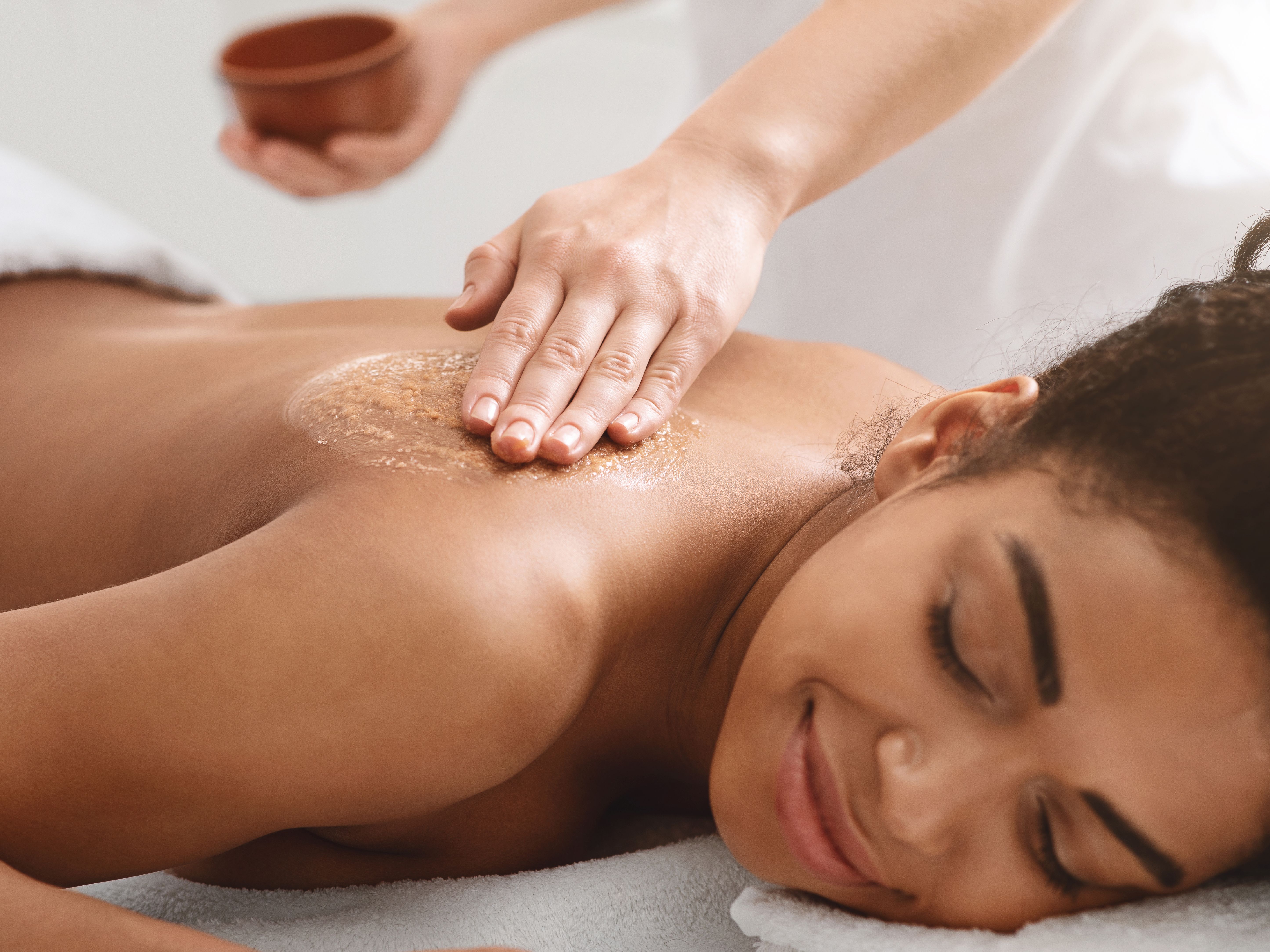 Woman receiving a relaxing back exfoliation treatment at a spa