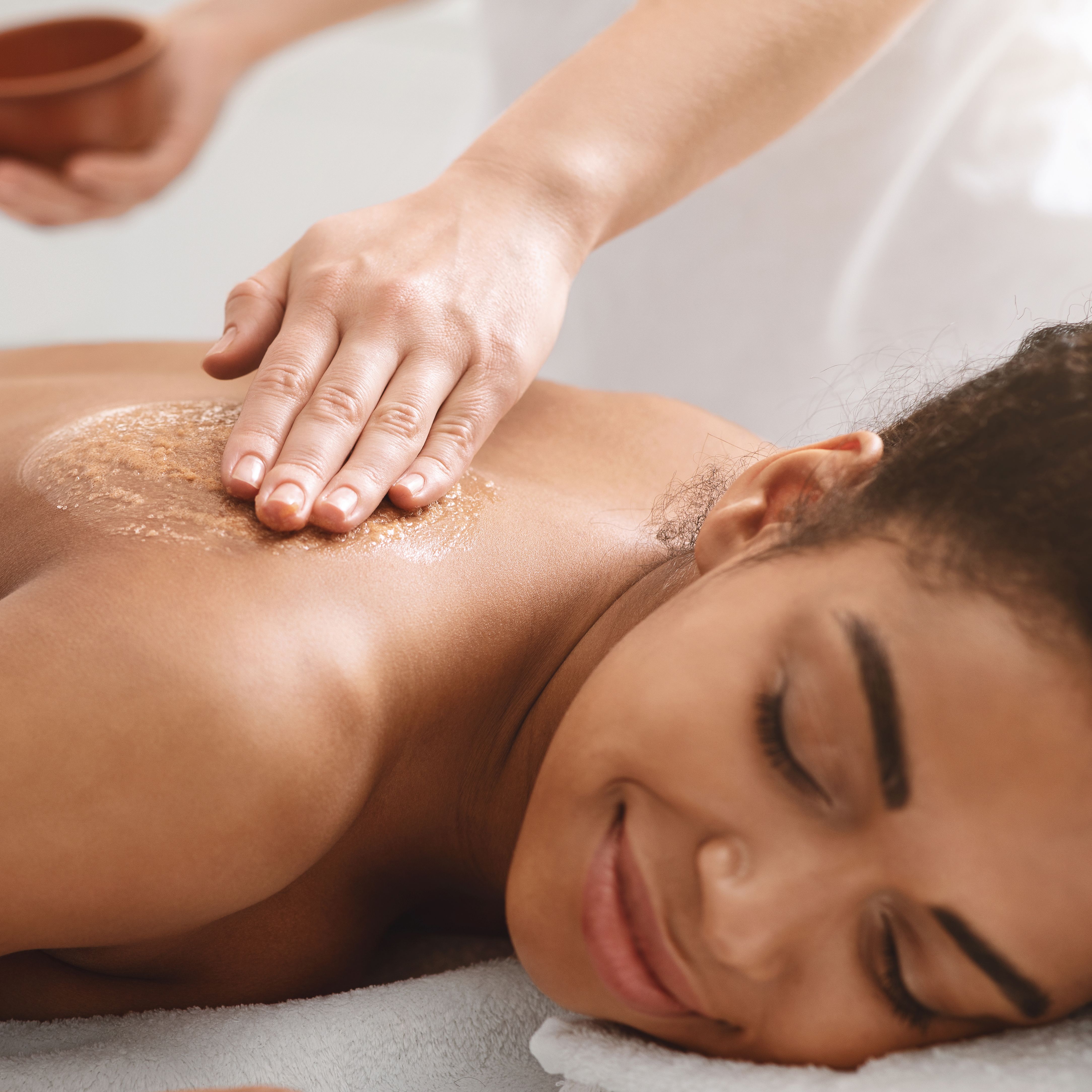 Woman receiving a relaxing back exfoliation treatment at a spa