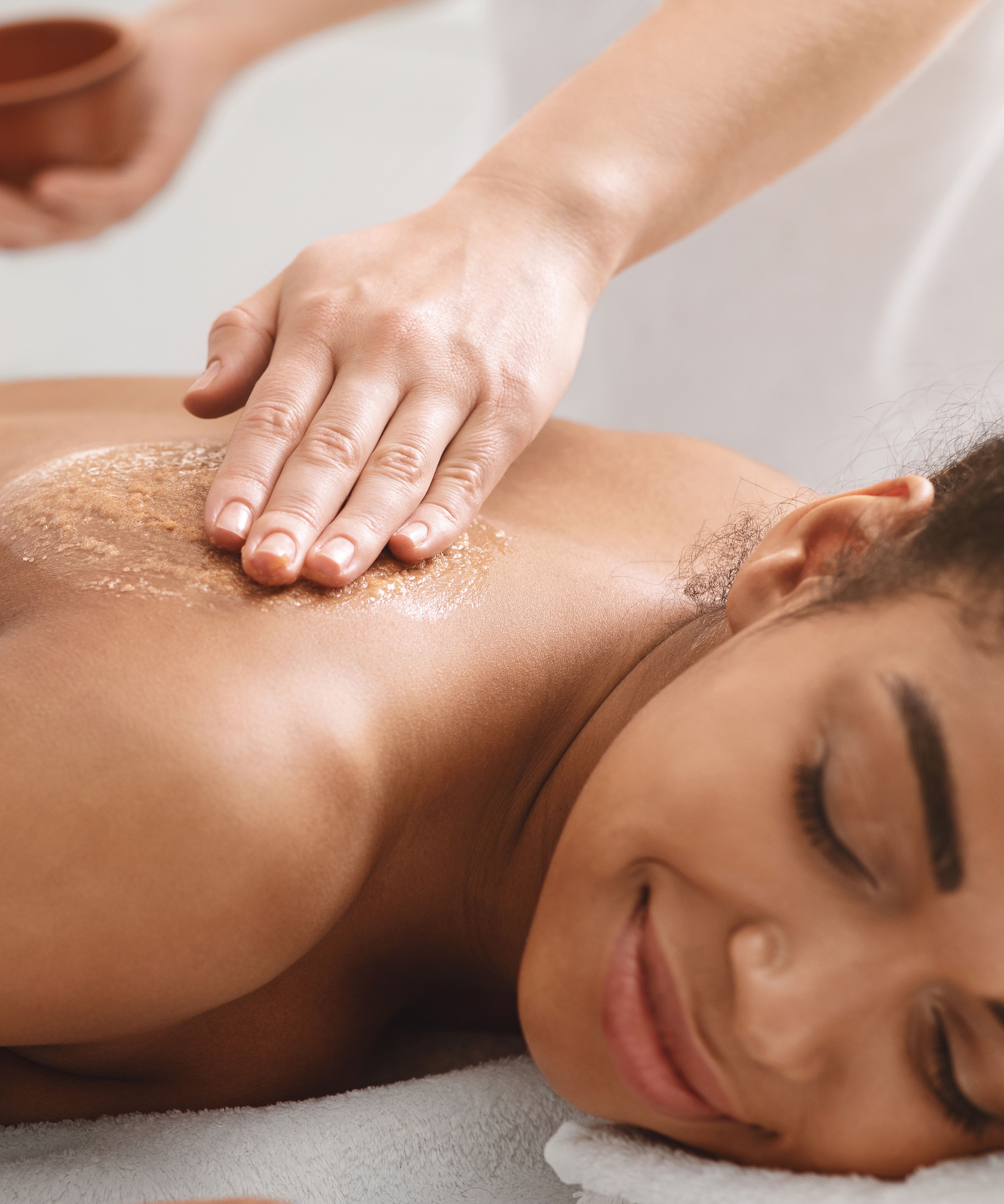 Woman receiving a relaxing back exfoliation treatment at a spa