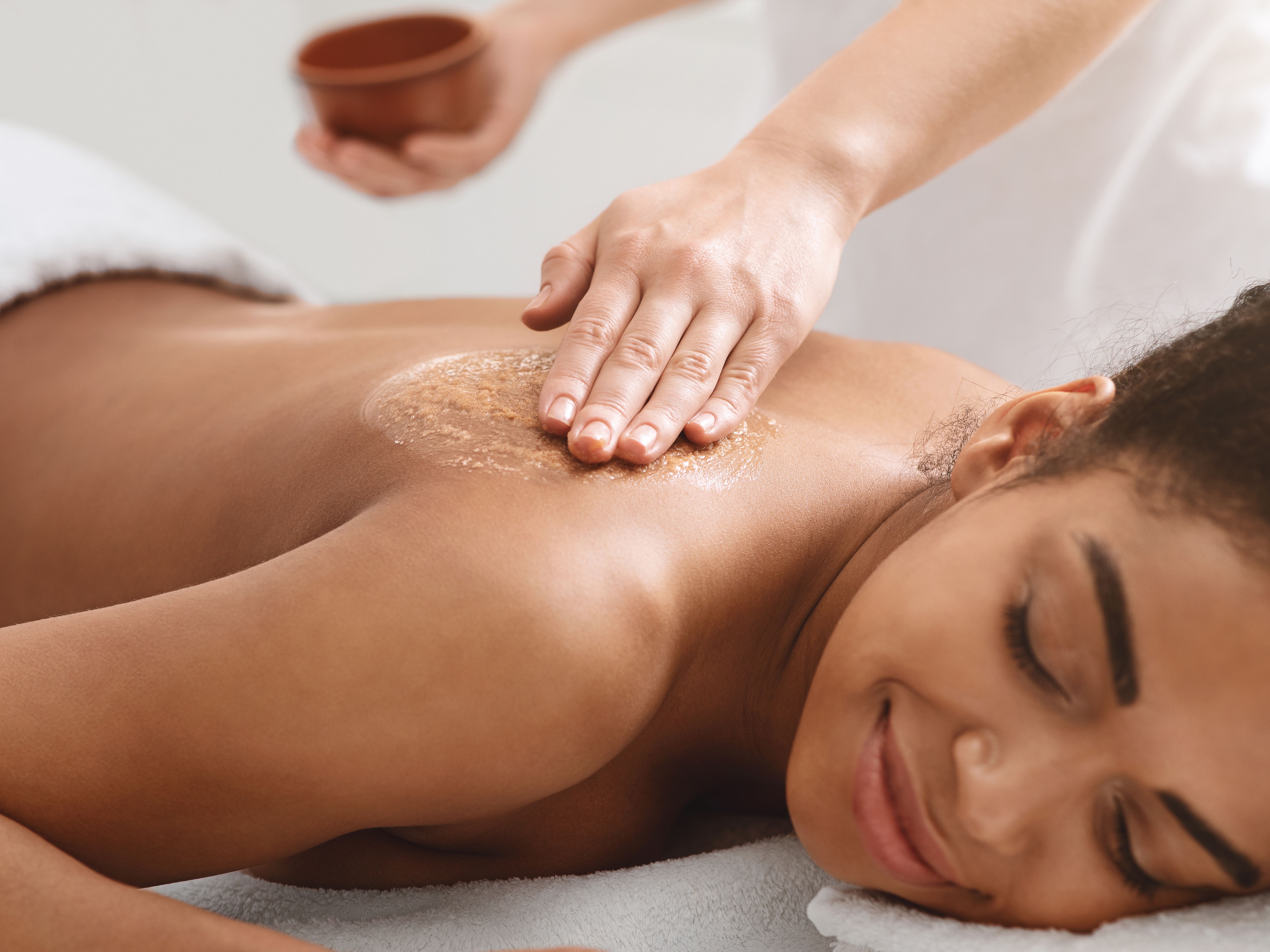Woman receiving a relaxing back exfoliation treatment at a spa