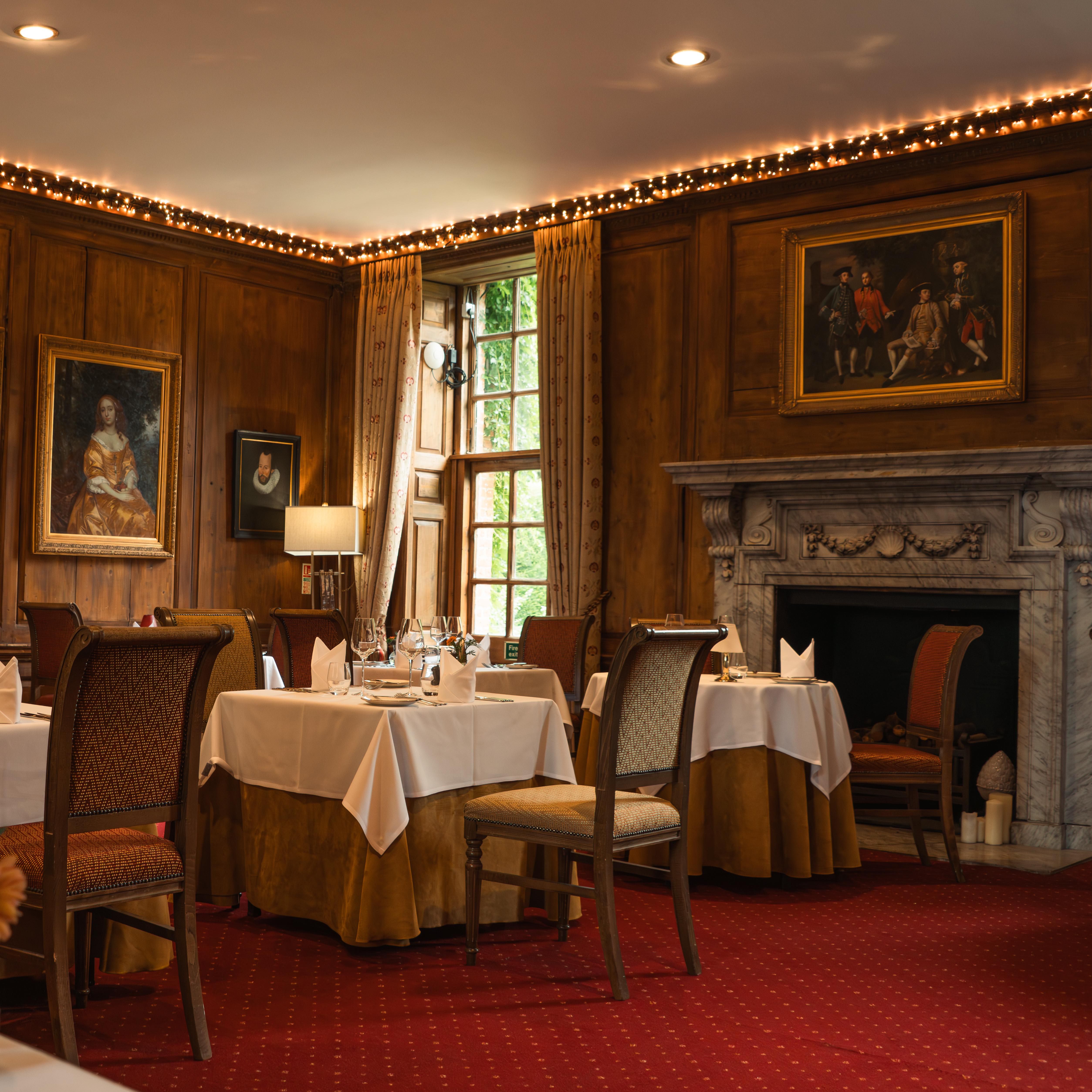 Elegant dining room with classic paintings, fireplace, and neatly set tables