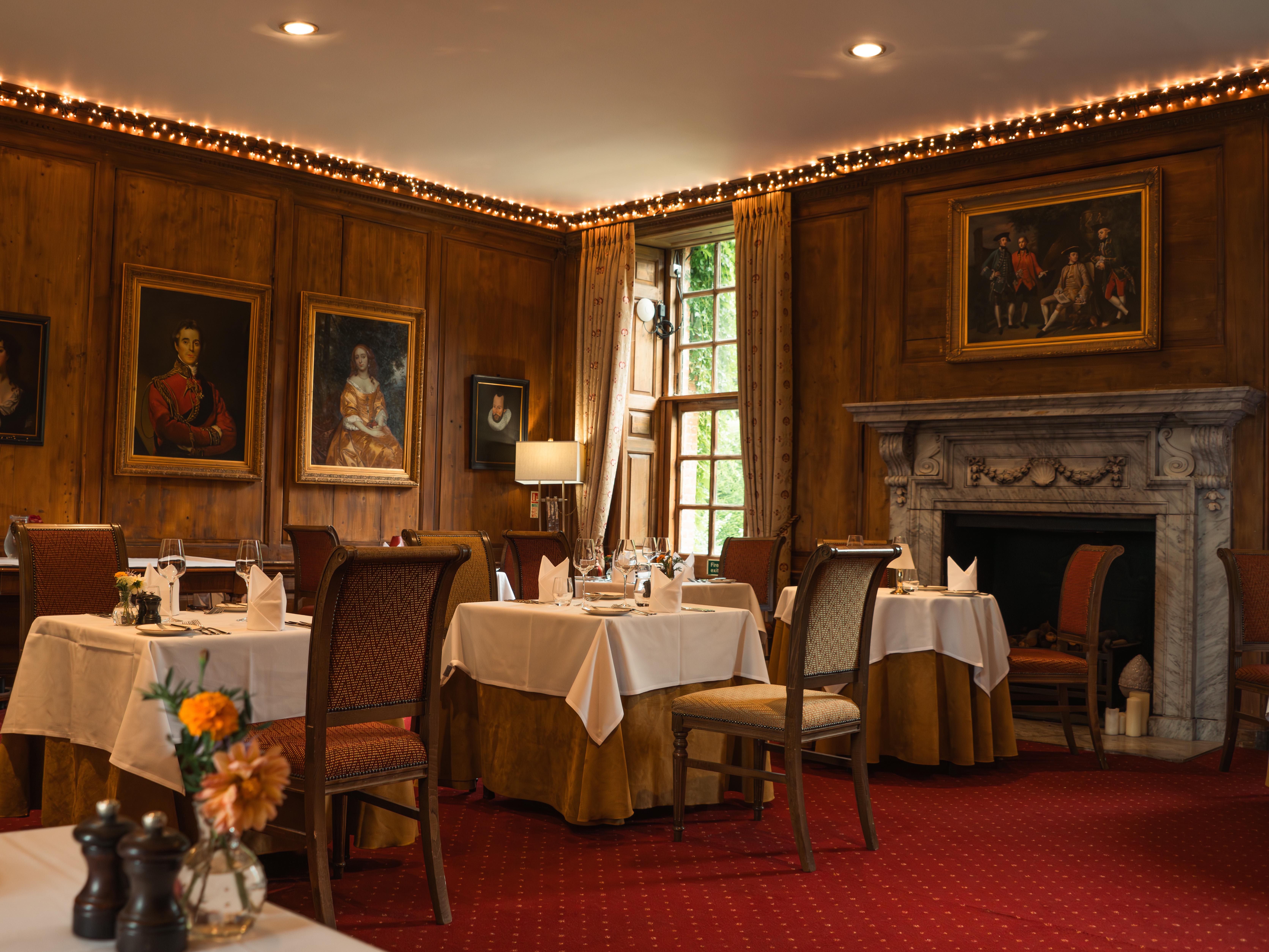 Elegant dining room with classic paintings, fireplace, and neatly set tables