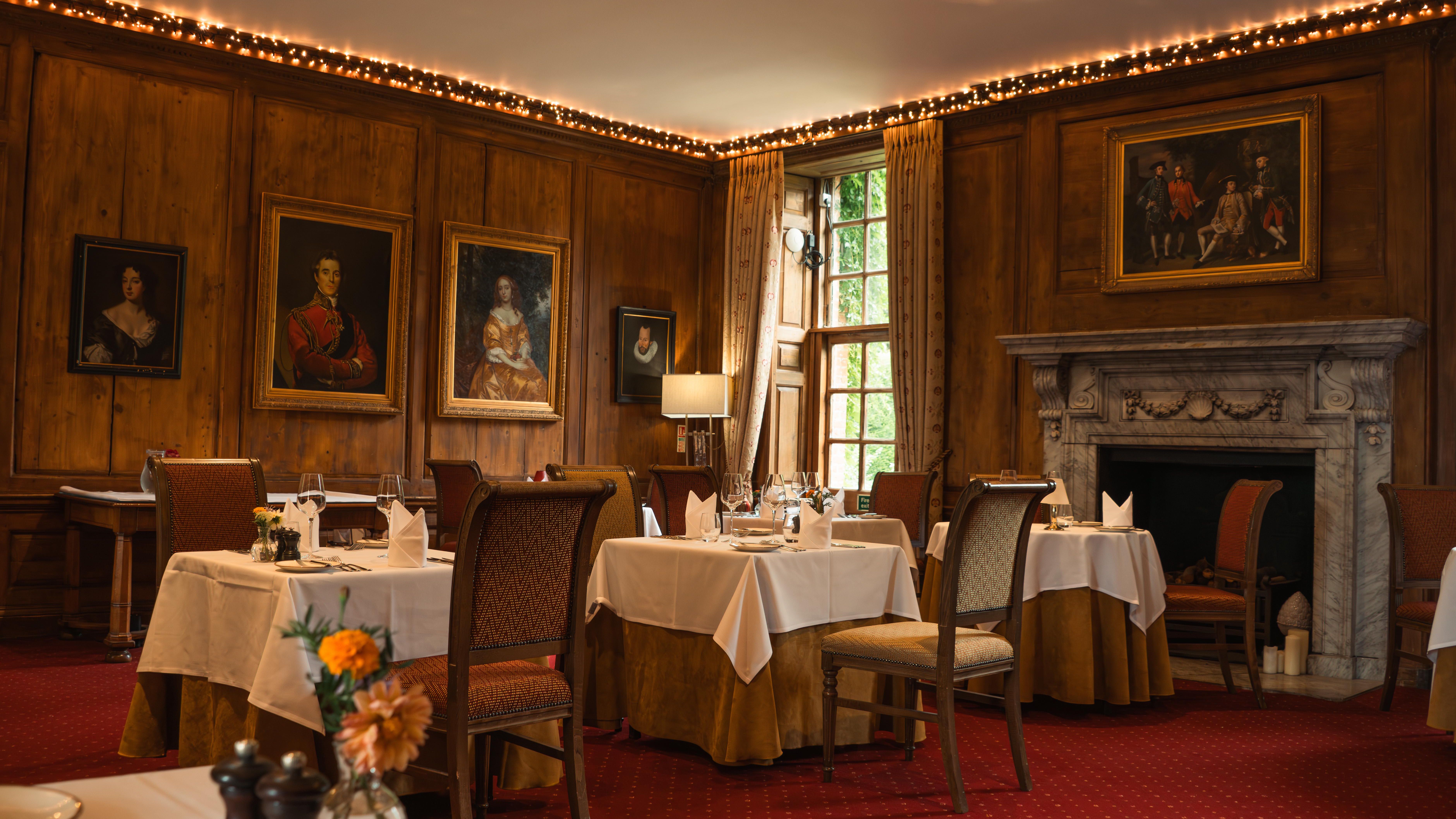 Elegant dining room with classic paintings, fireplace, and neatly set tables