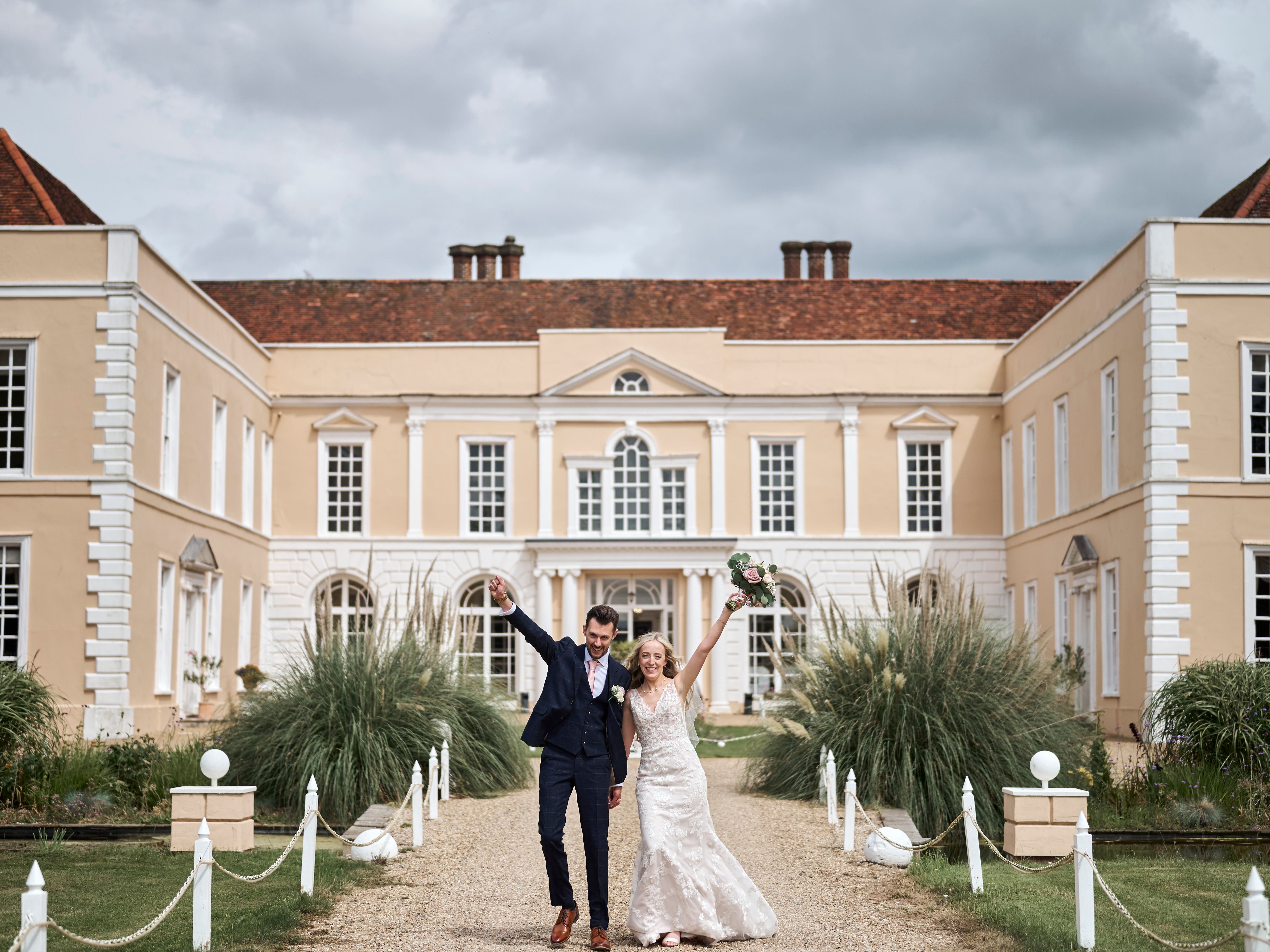 Bride and groom celebrate outside a grand country manor on their wedding day.