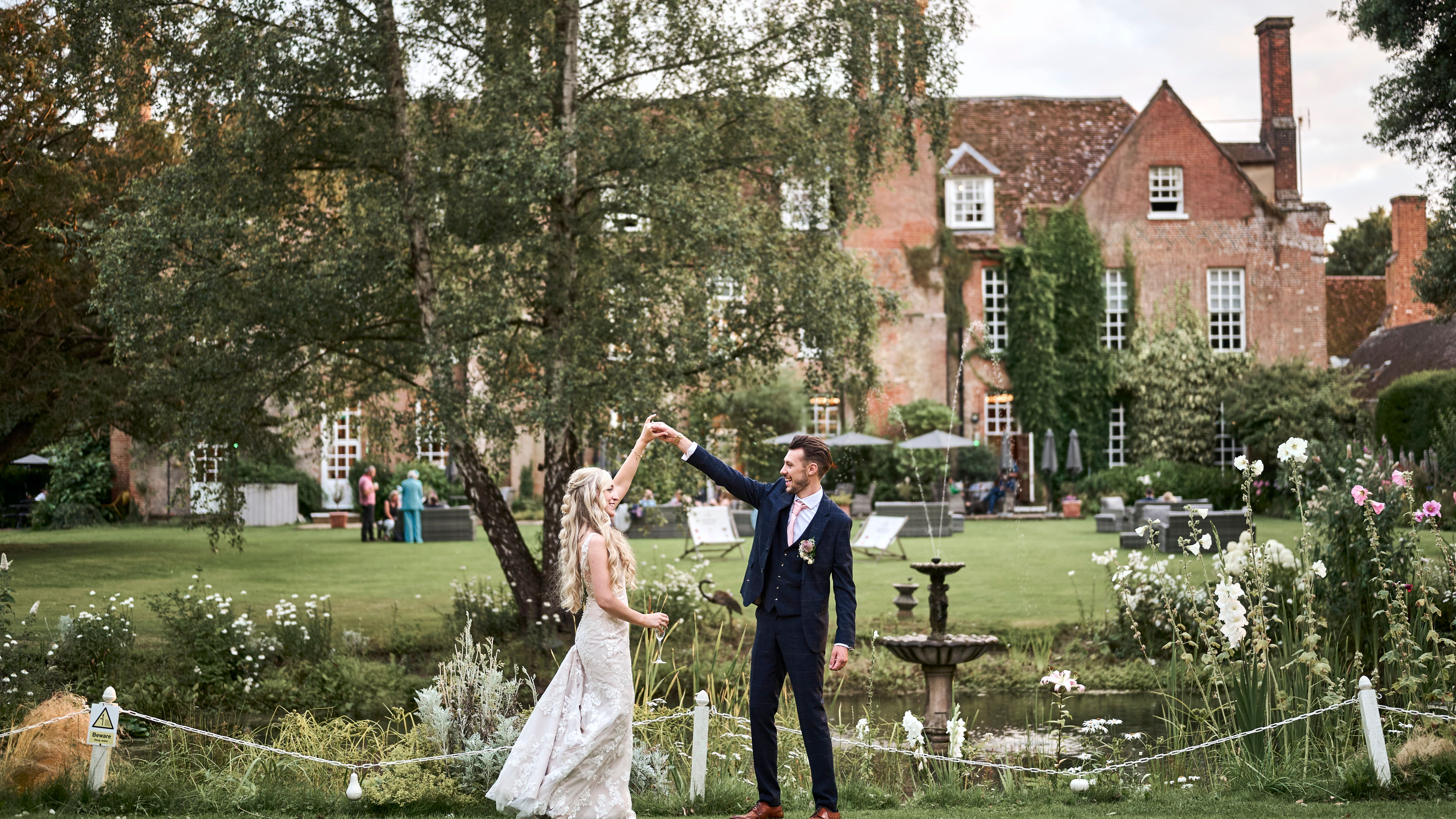 Bride and groom celebrating their marriage in the beautiful, landscaped gardens of Hintlesham Hall wedding venue in Ipswich.