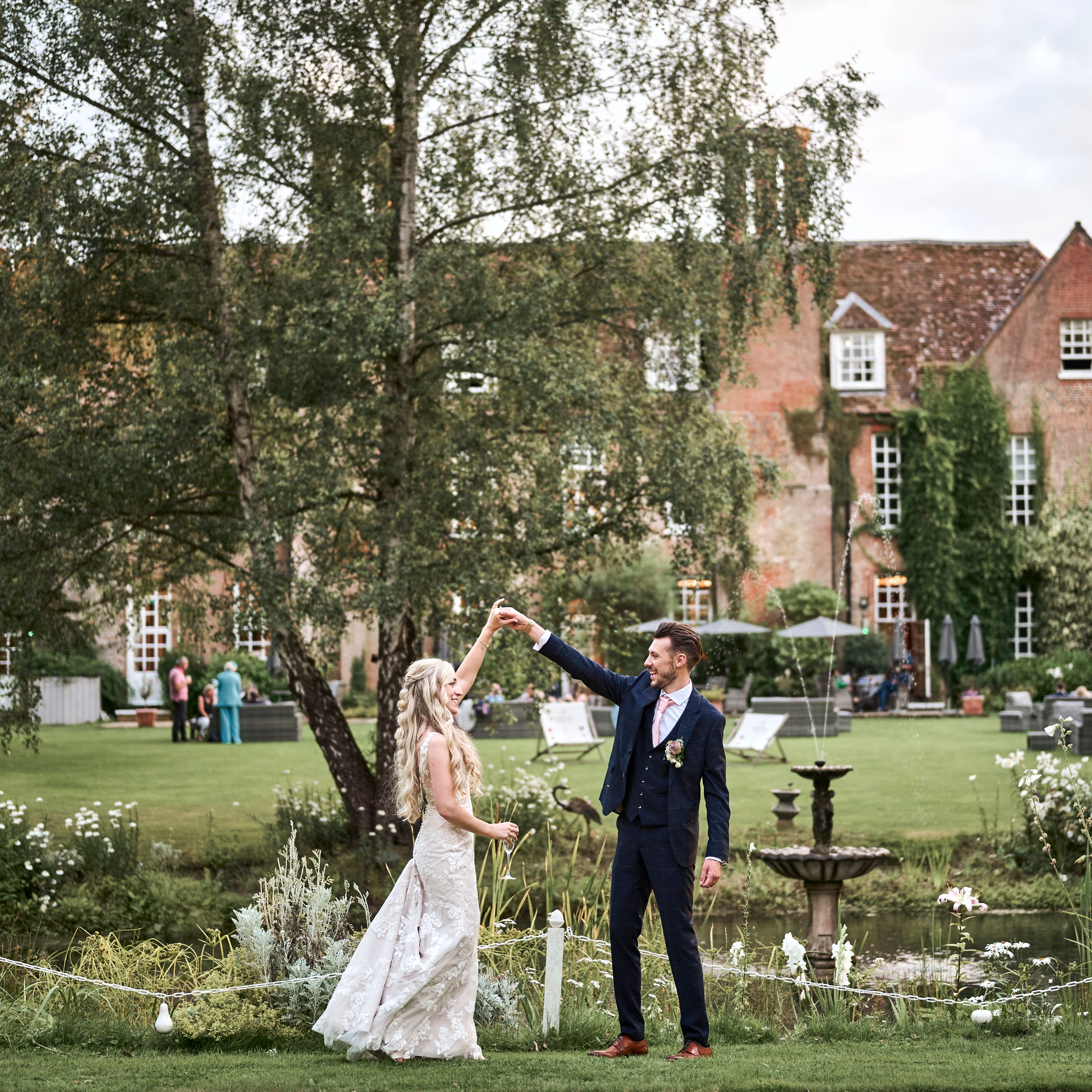Bride and groom celebrating their marriage in the beautiful, landscaped gardens of Hintlesham Hall wedding venue in Ipswich.