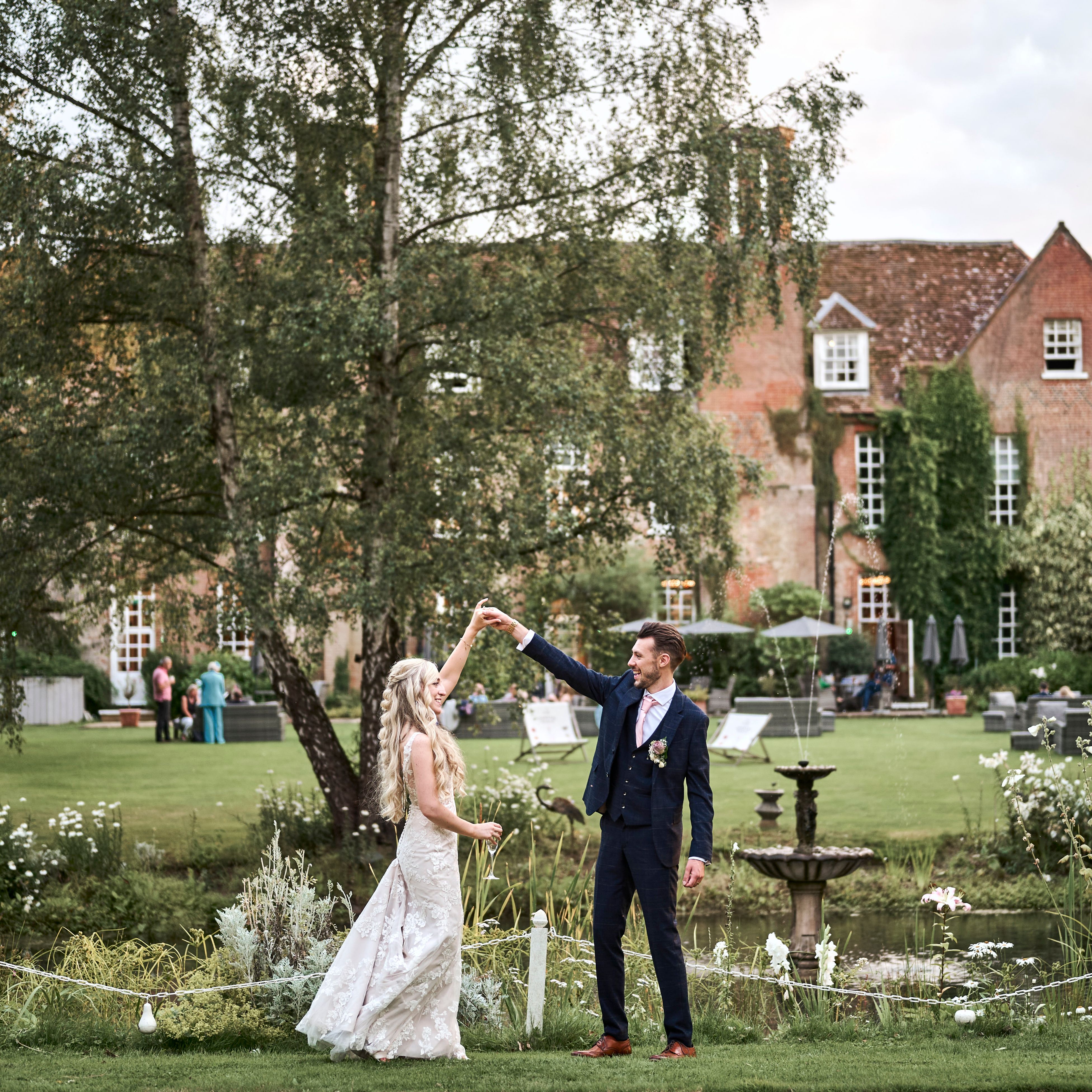 Bride and groom celebrating their marriage in the beautiful, landscaped gardens of Hintlesham Hall wedding venue in Ipswich.
