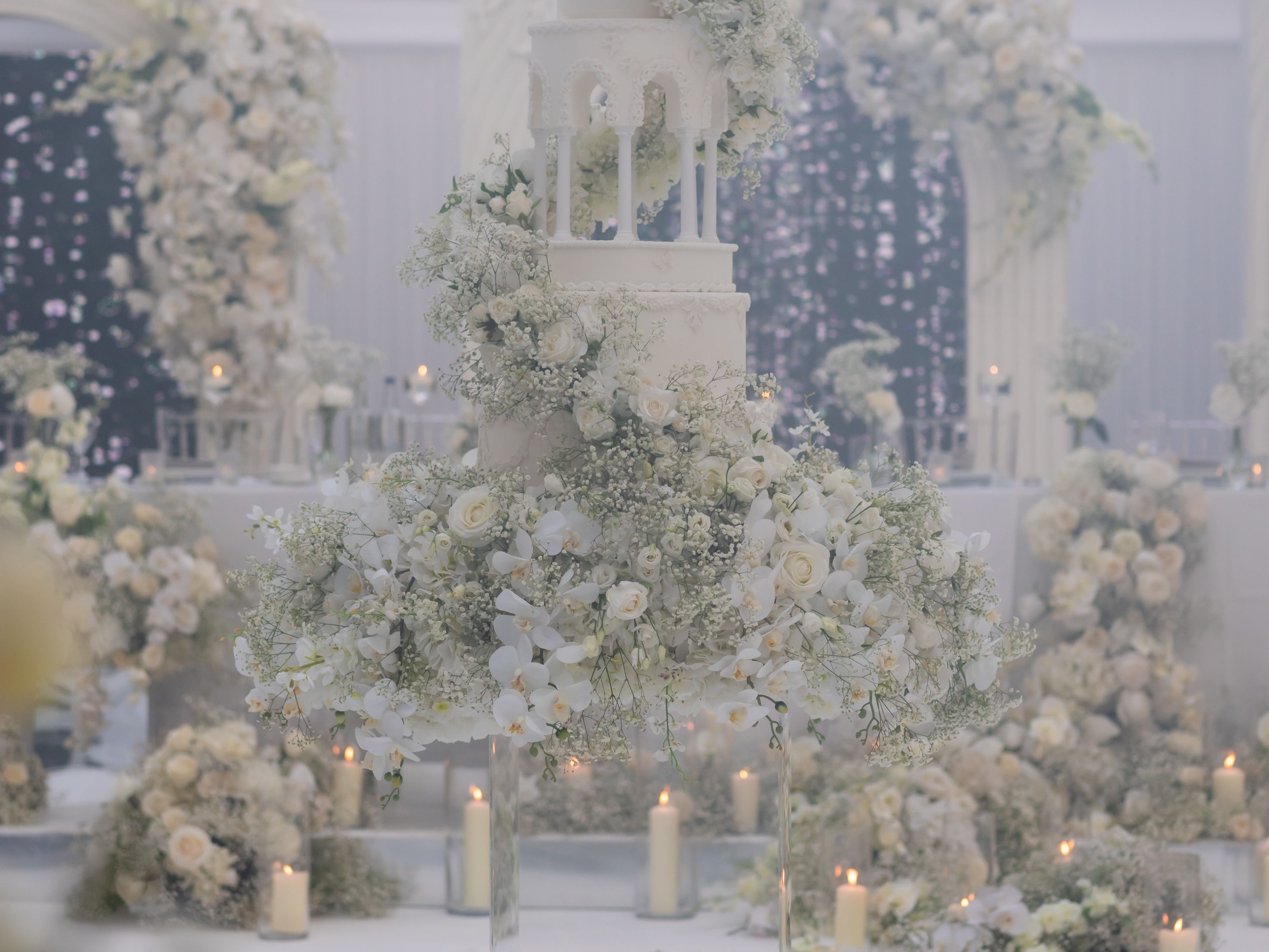Elegant white wedding cake decorated with cascading flowers at a luxurious wedding venue