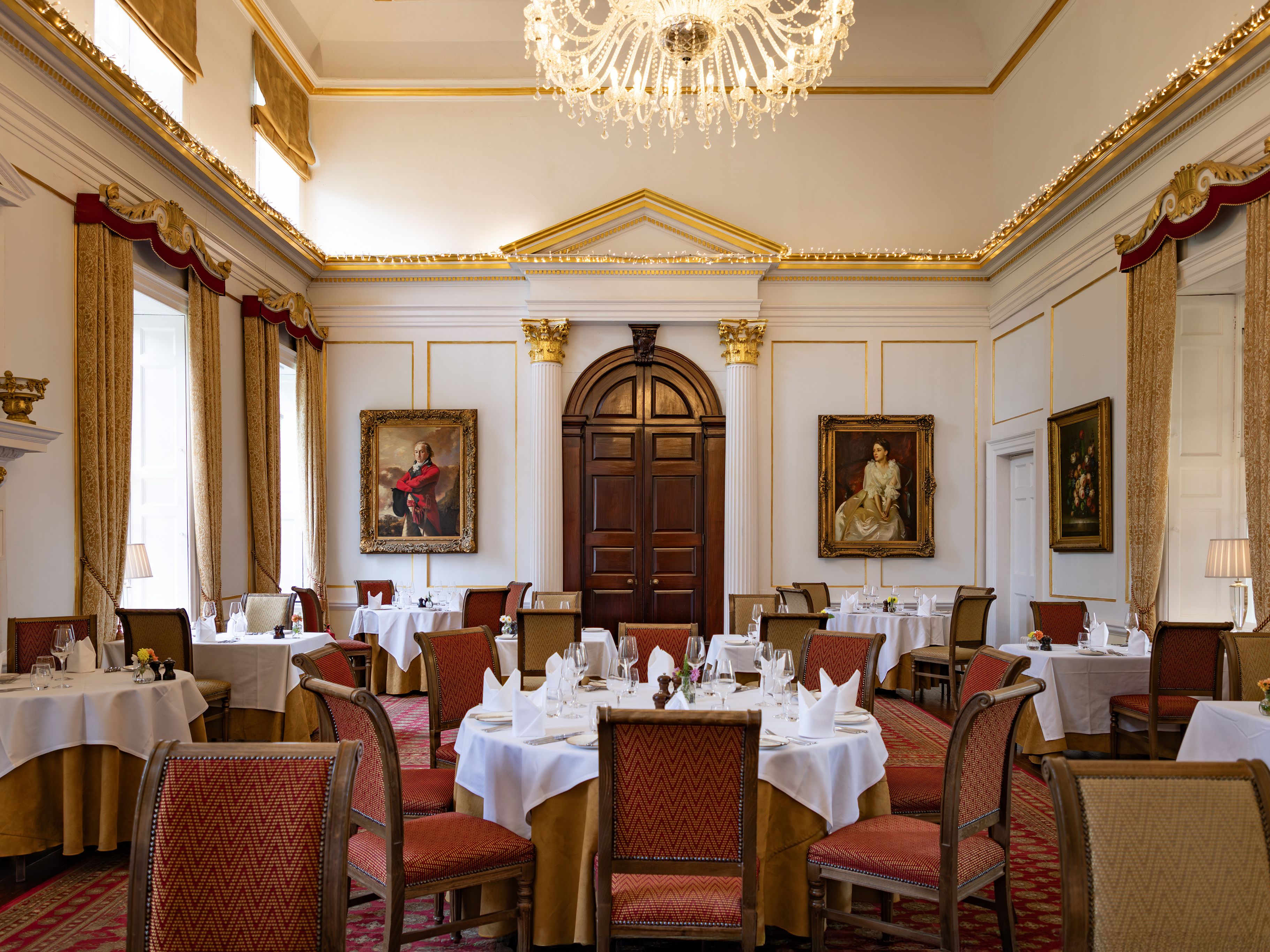 Elegant dining room with classical decor, chandeliers, and formal table settings.