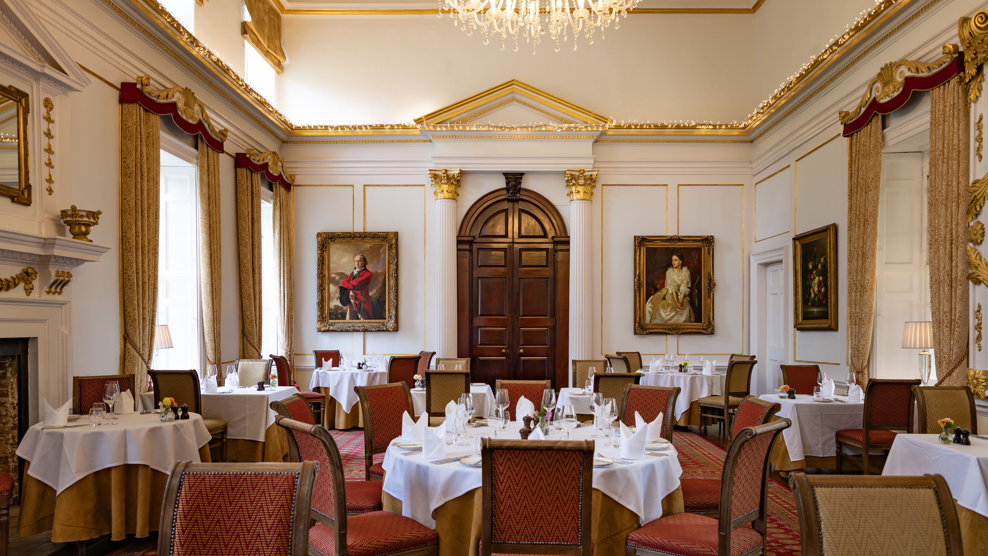 Elegant dining room with classical decor, chandeliers, and formal table settings.