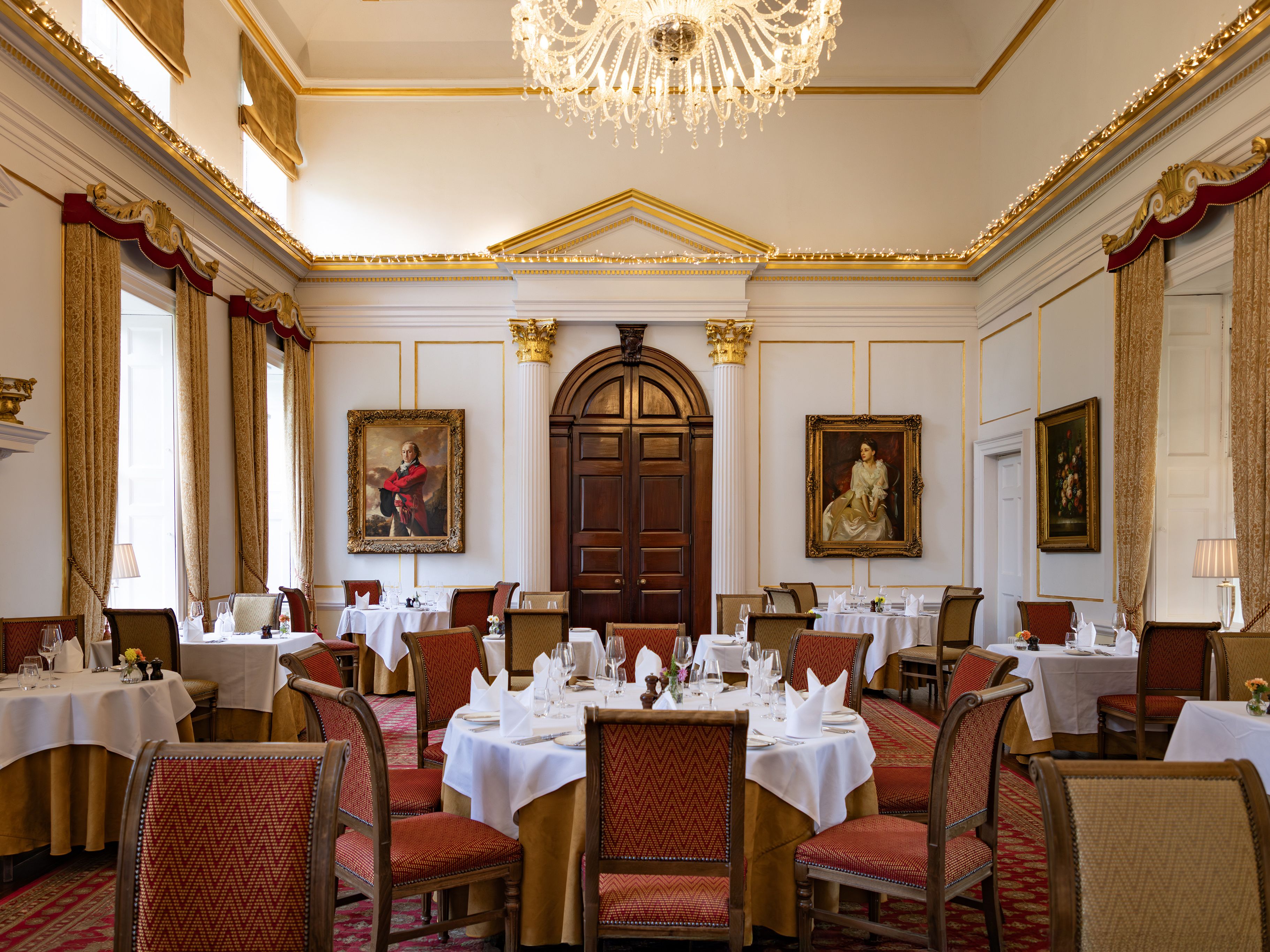 Elegant dining room with classical decor, chandeliers, and formal table settings.