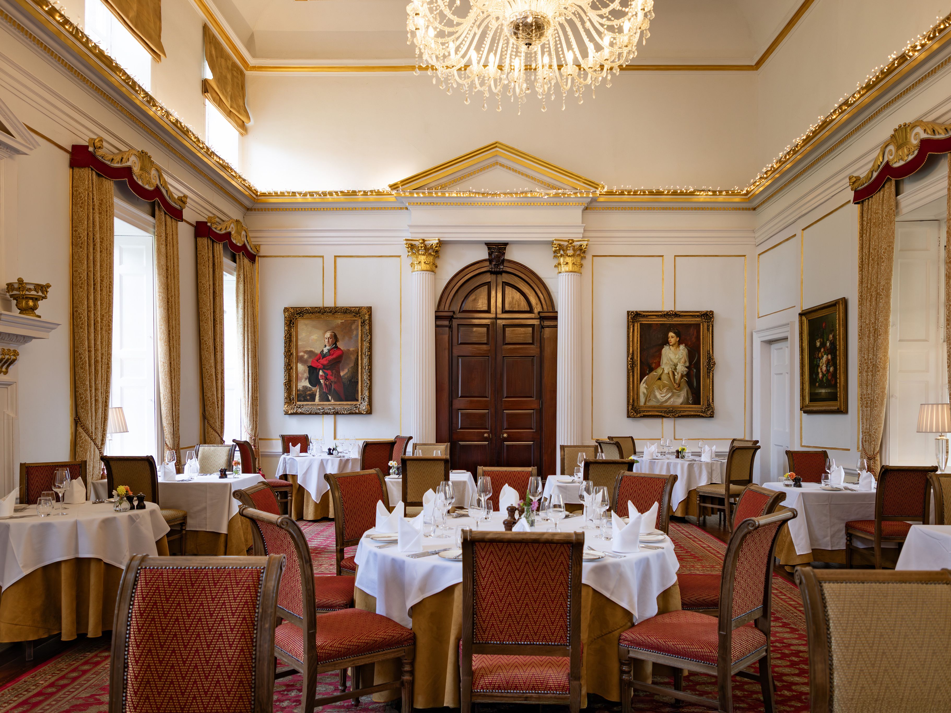 Elegant dining room with classical decor, chandeliers, and formal table settings.