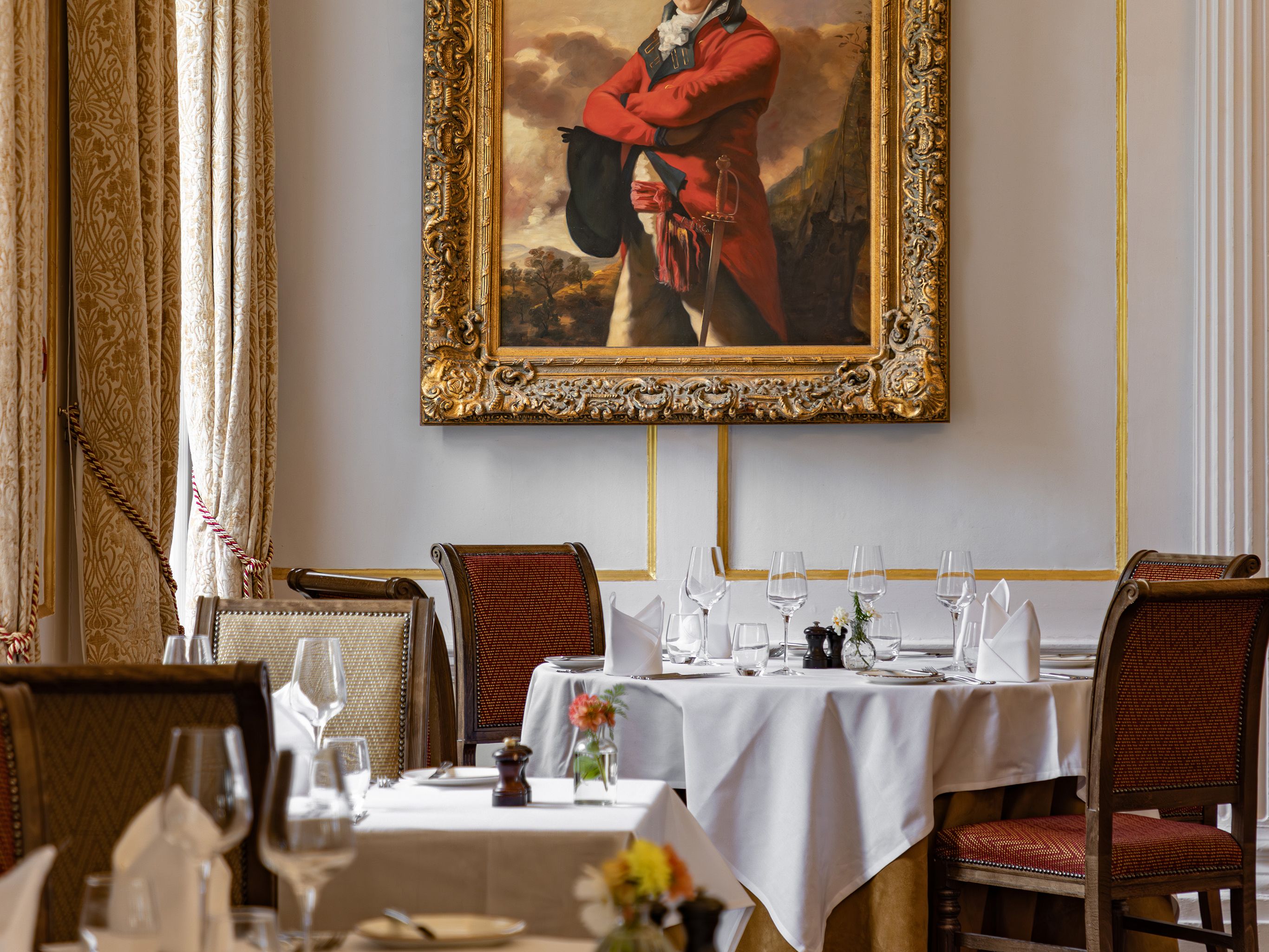 Elegant dining room with classic decor, featuring a large, ornate framed portrait of a man in historical attire on the wall.