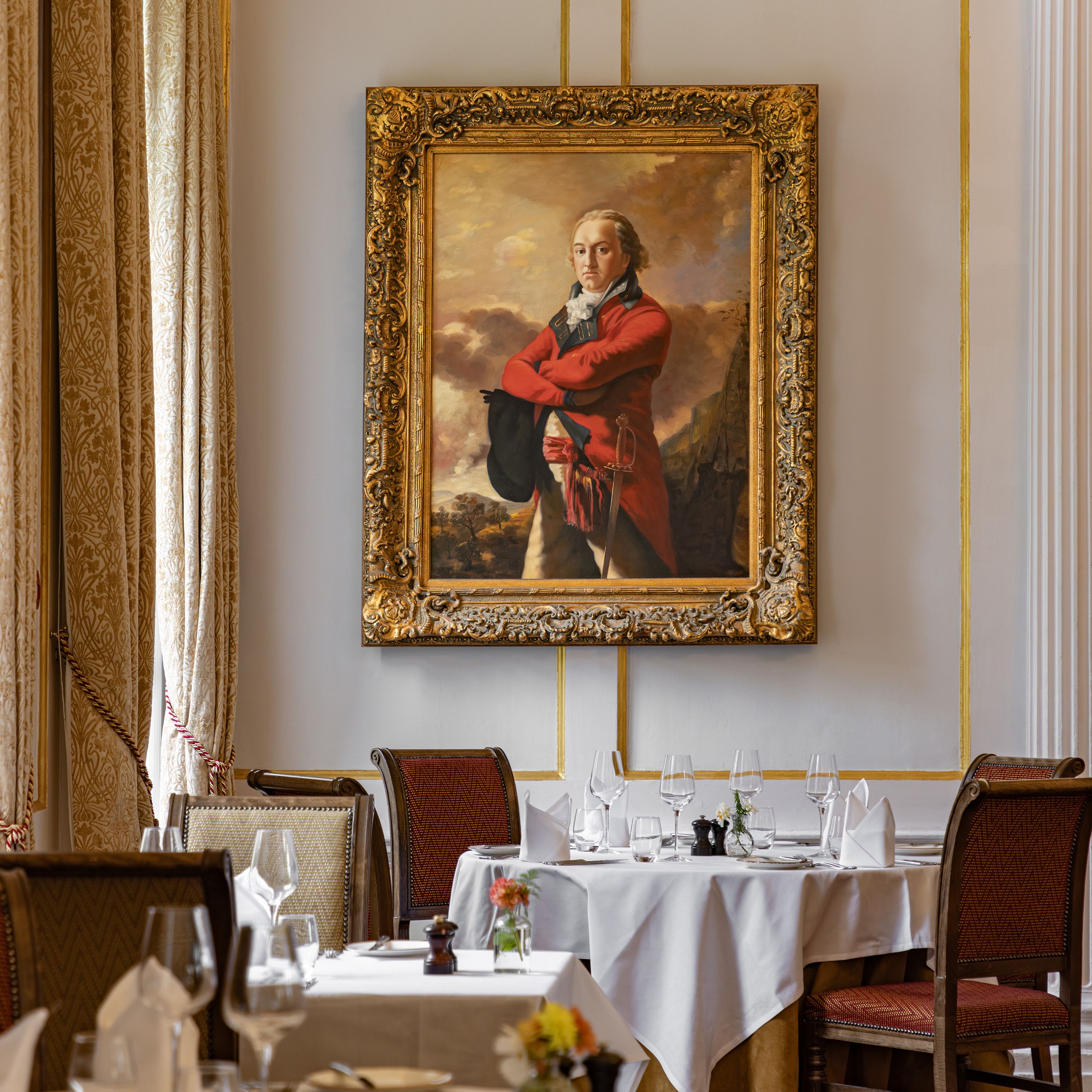 Elegant dining room with classic decor, featuring a large, ornate framed portrait of a man in historical attire on the wall.