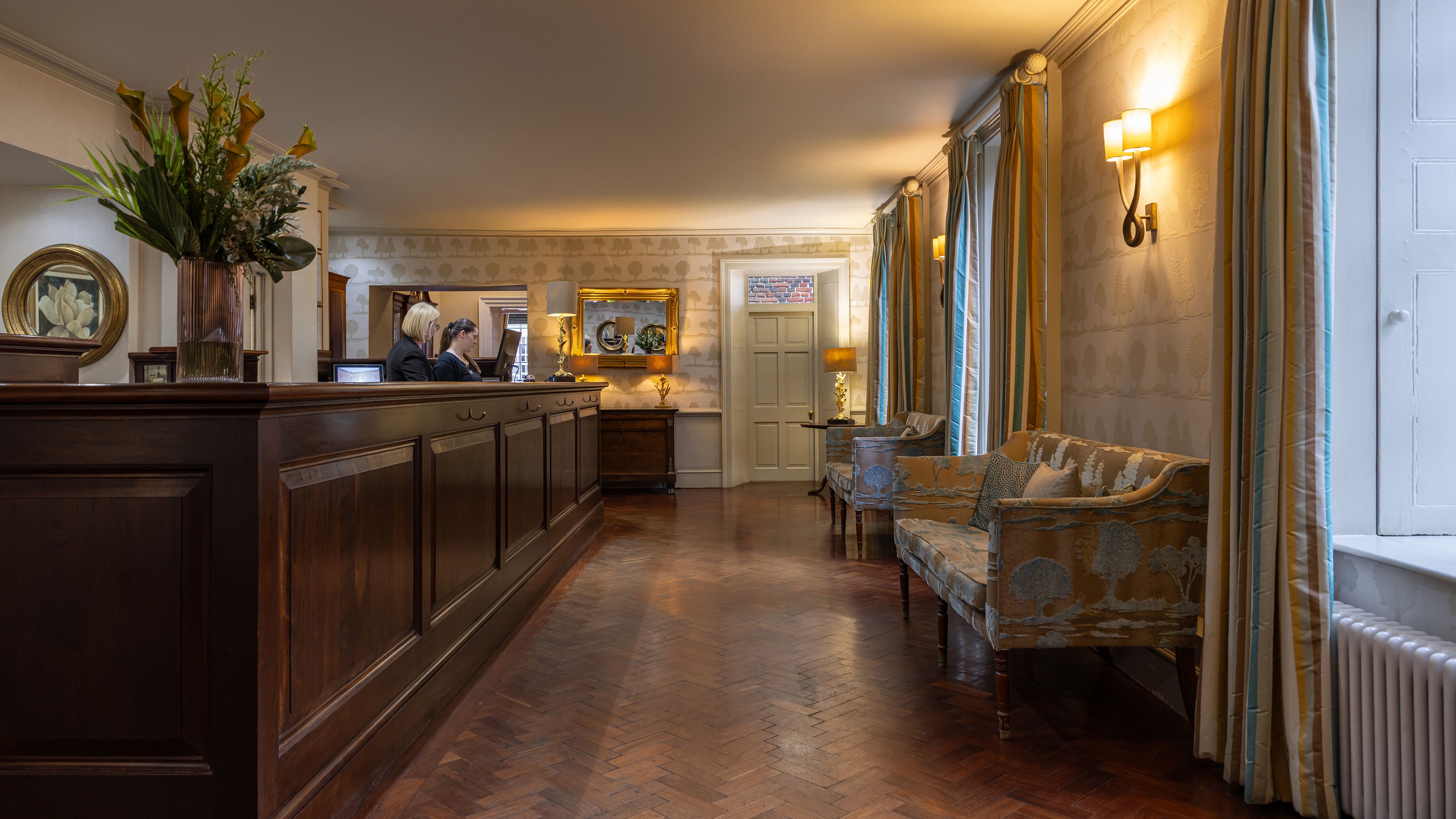 Elegant hotel reception area with wooden desk, comfortable seating, and warm lighting