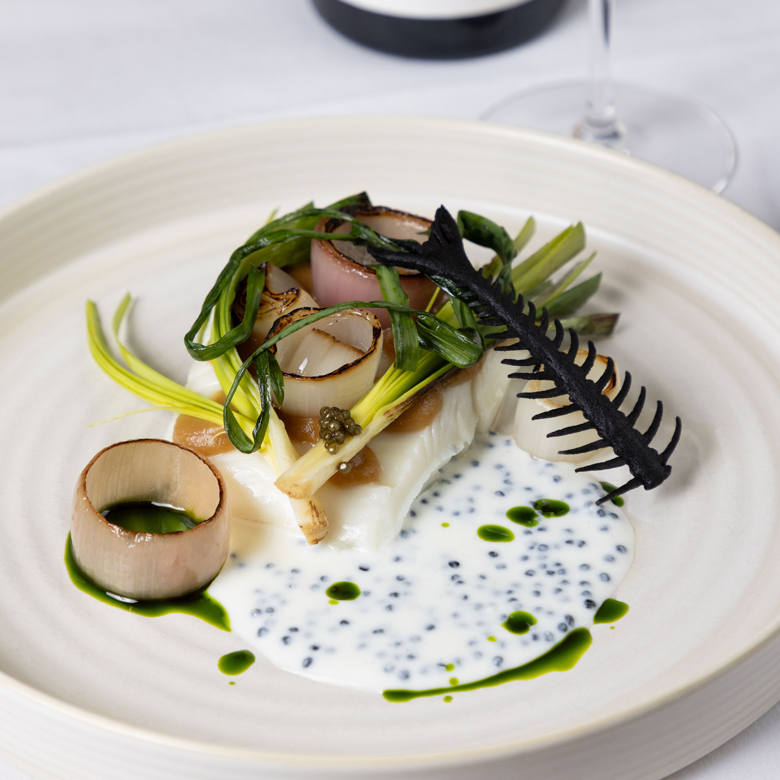 Gourmet fish dish with grilled vegetables, sauce, and wine