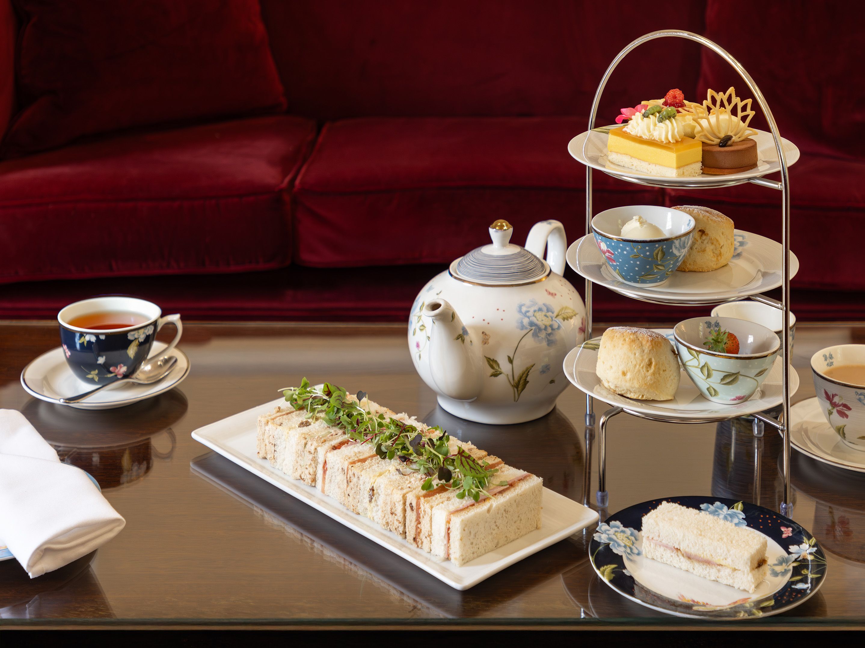 Afternoon tea set with sandwiches, scones, pastries, and tea on a table