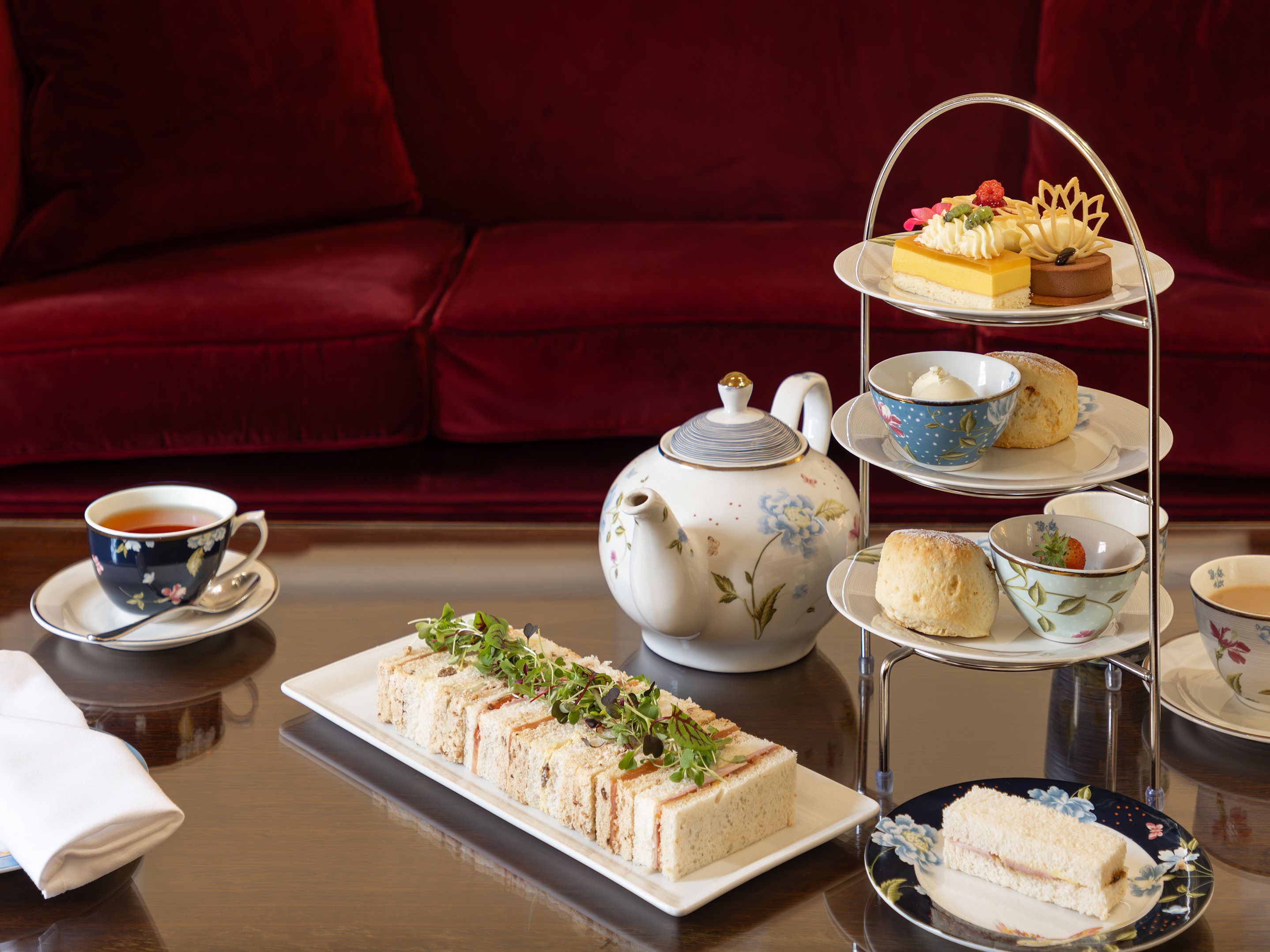 Afternoon tea set with sandwiches, scones, pastries, and tea on a table