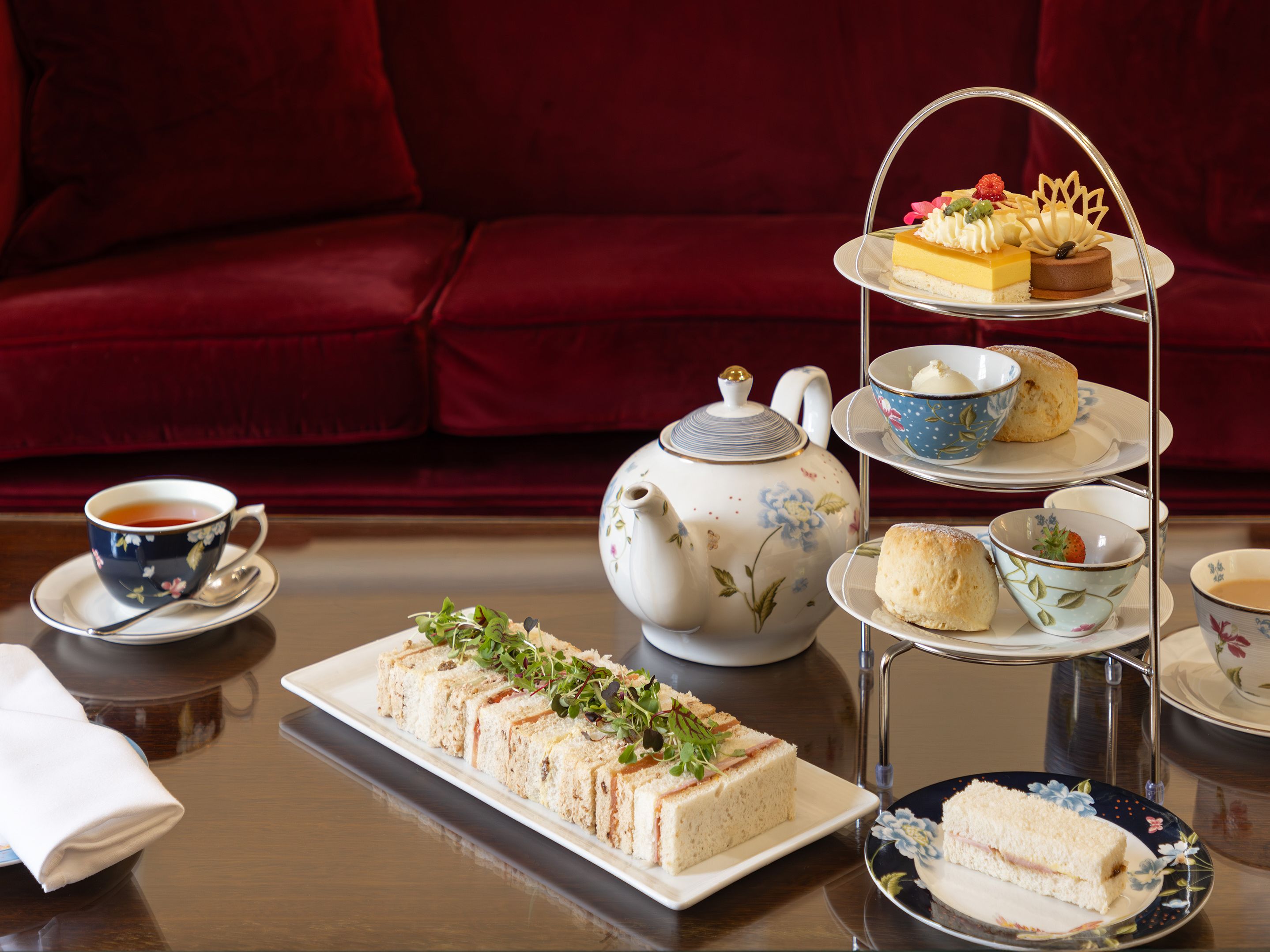 Afternoon tea set with sandwiches, scones, pastries, and tea on a table