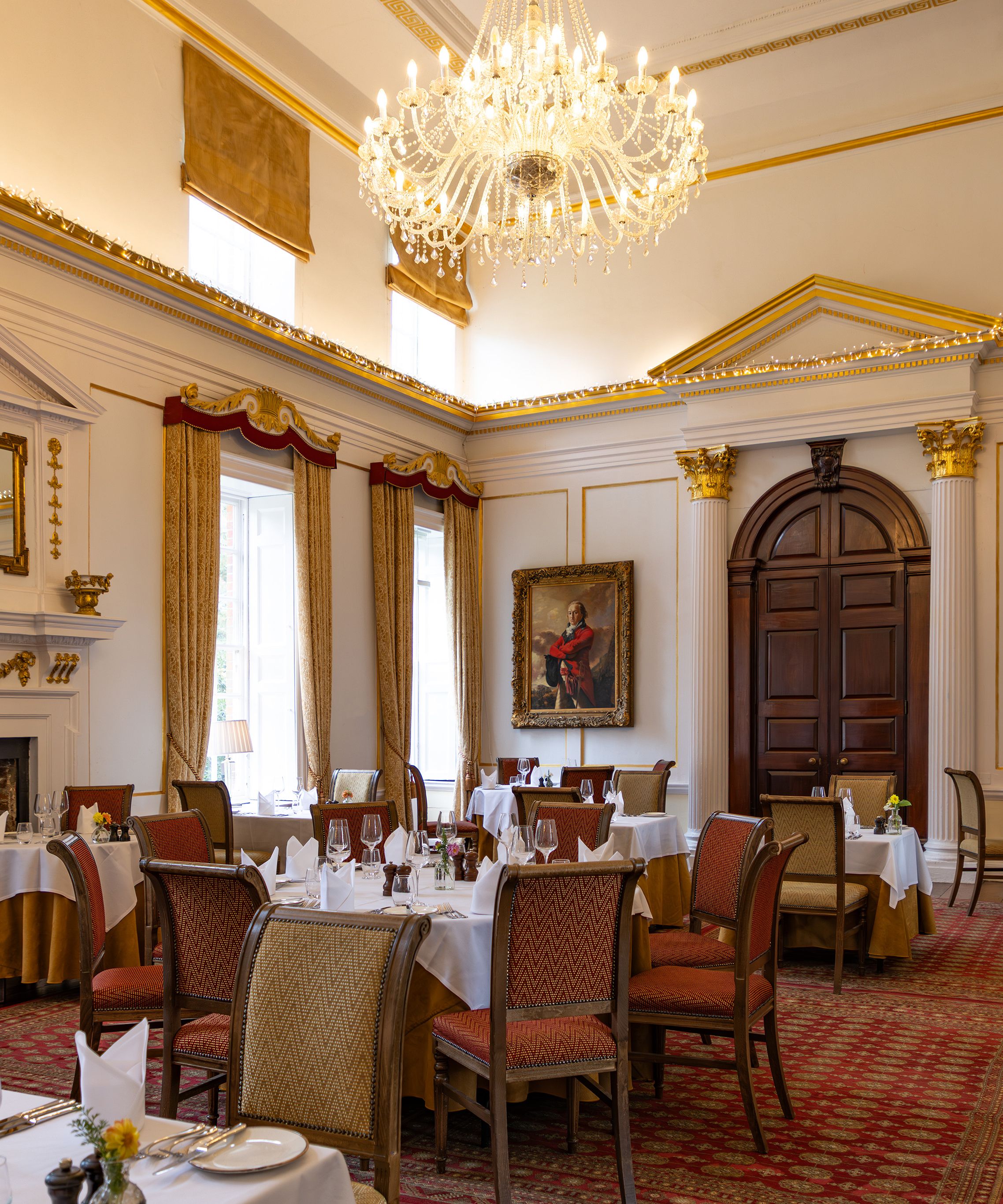Elegant dining room with chandelier, classical paintings, and arranged tables