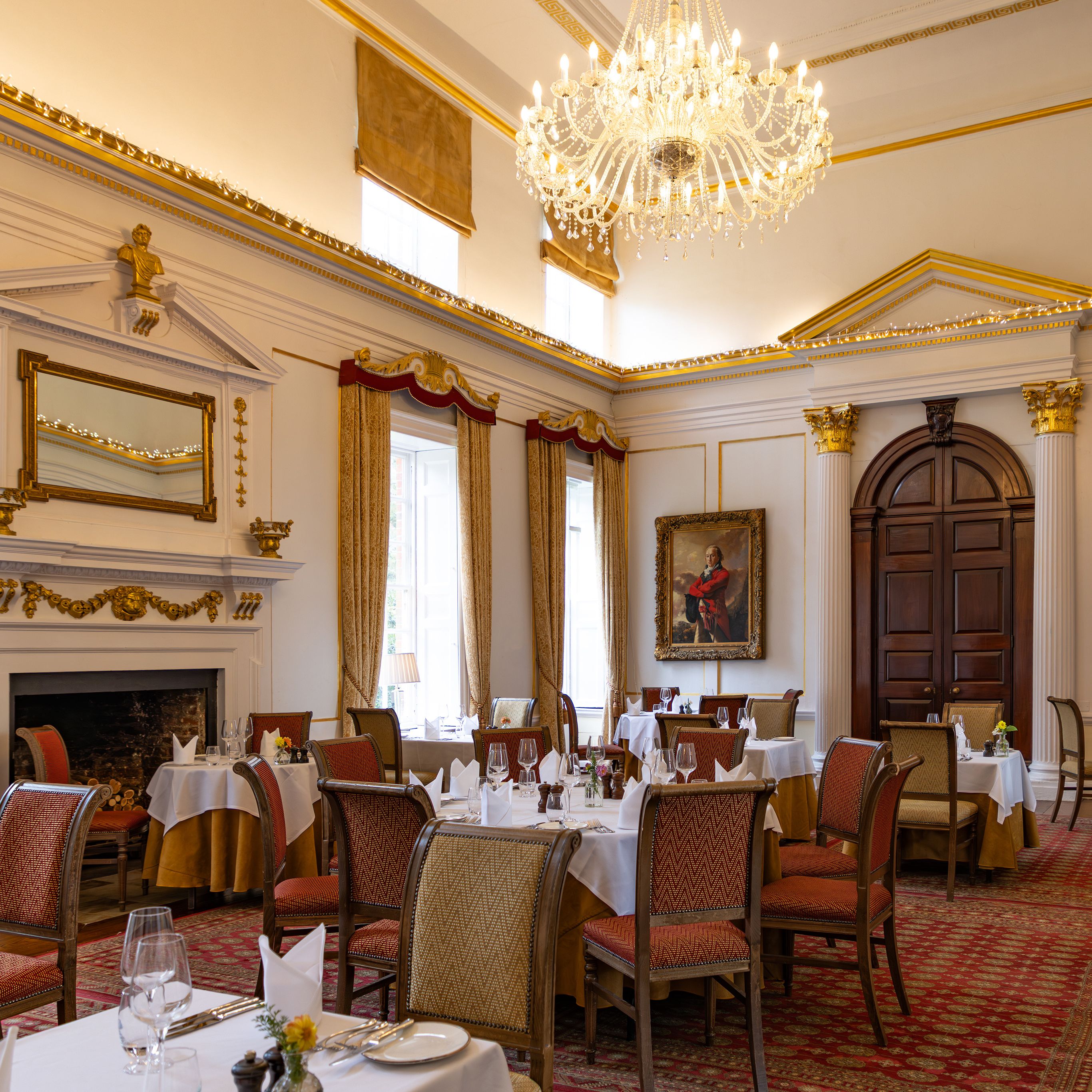 Elegant dining room with chandelier, classical paintings, and arranged tables