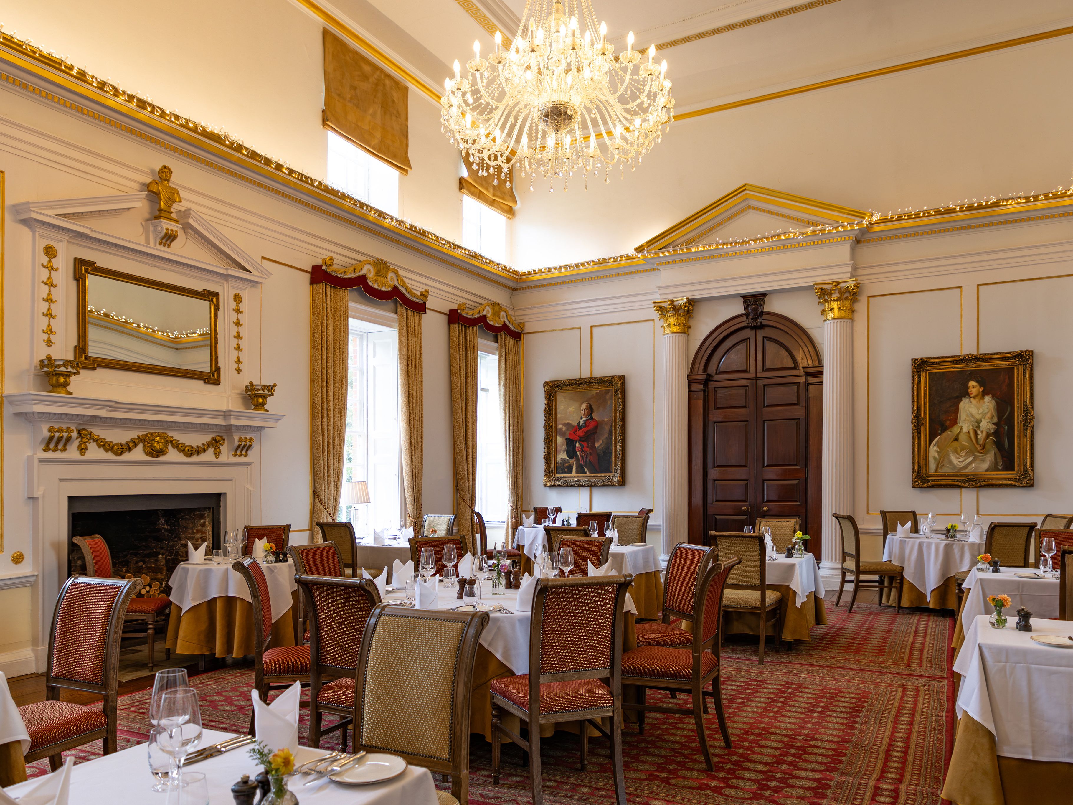 Elegant dining room with chandelier, classical paintings, and arranged tables