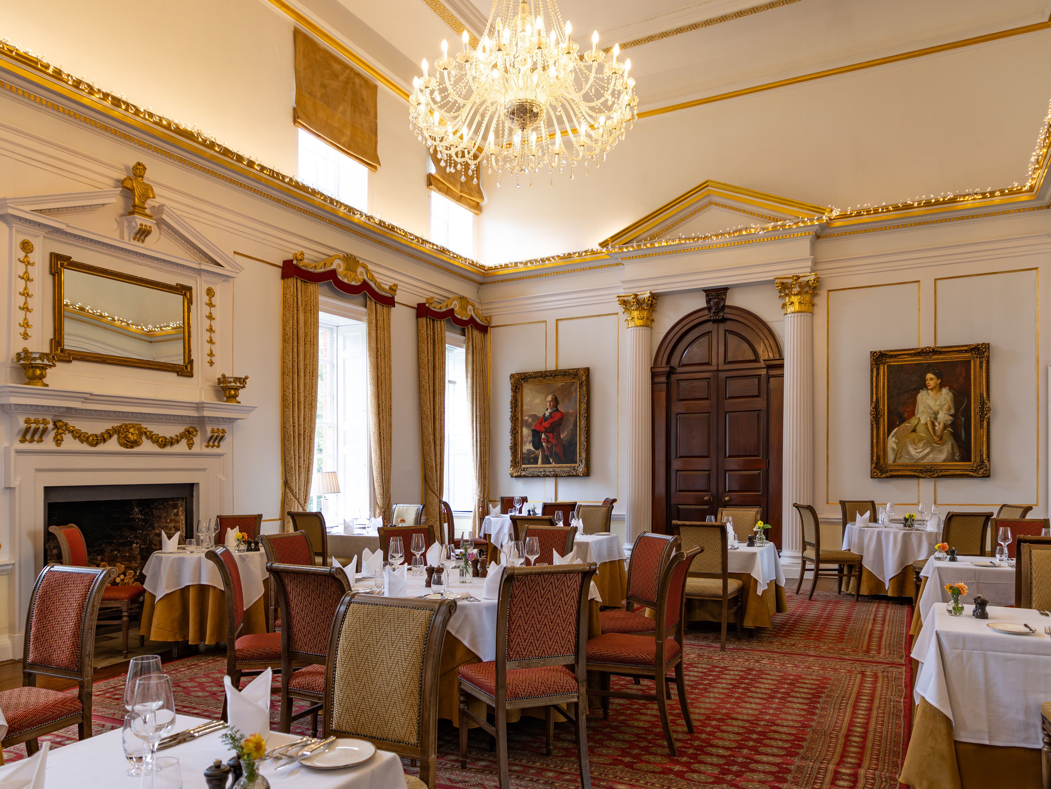 Elegant dining room with chandelier, classical paintings, and arranged tables
