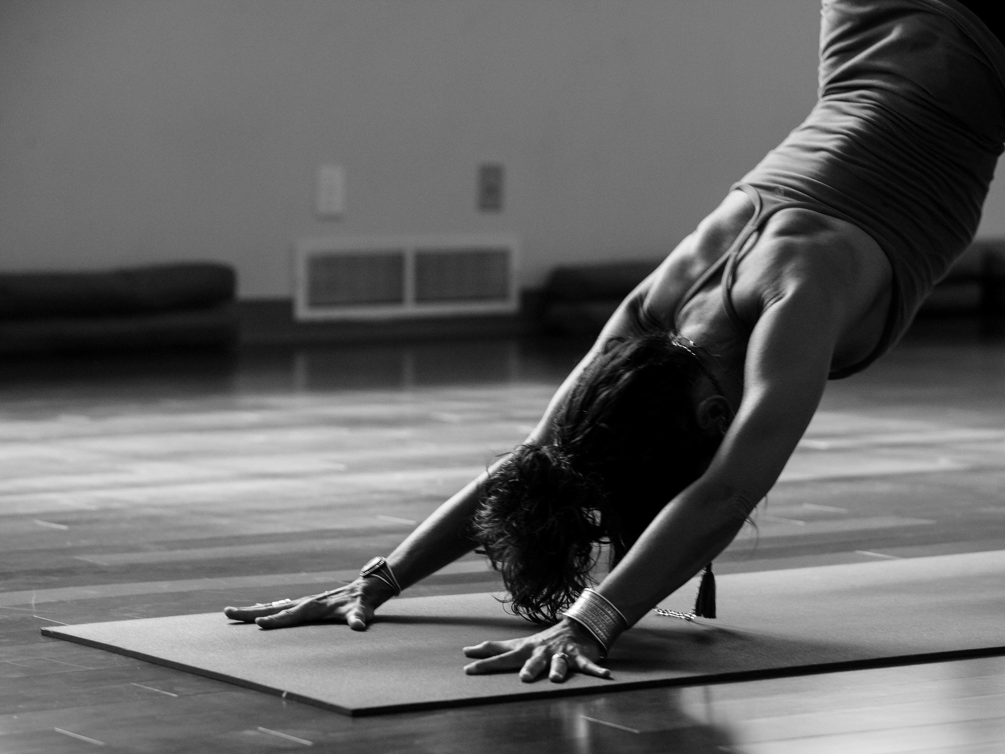 Person practicing yoga in downward dog pose on a mat in a studio