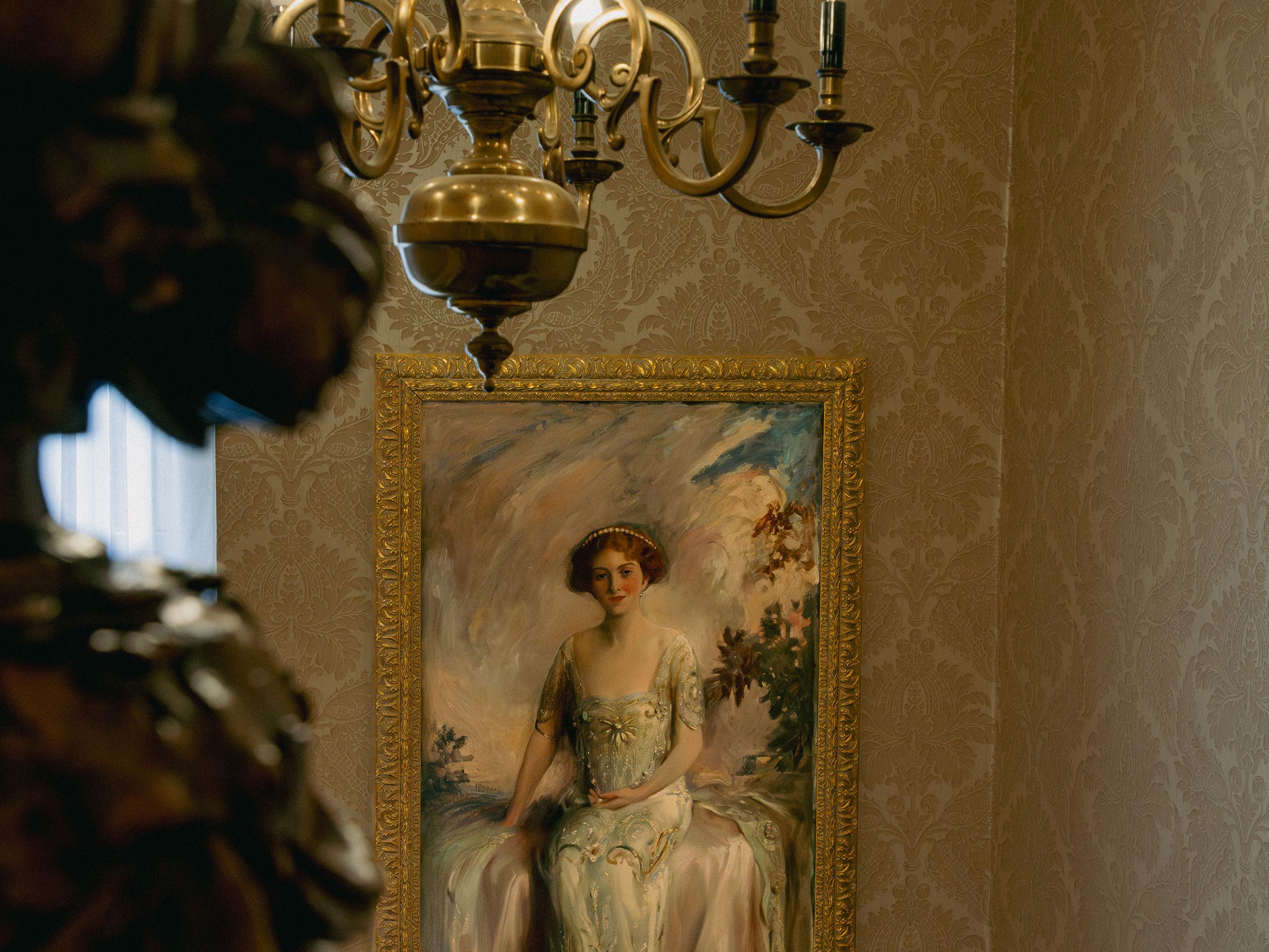 Elegant chandelier and framed portrait of a seated woman in a classical interior