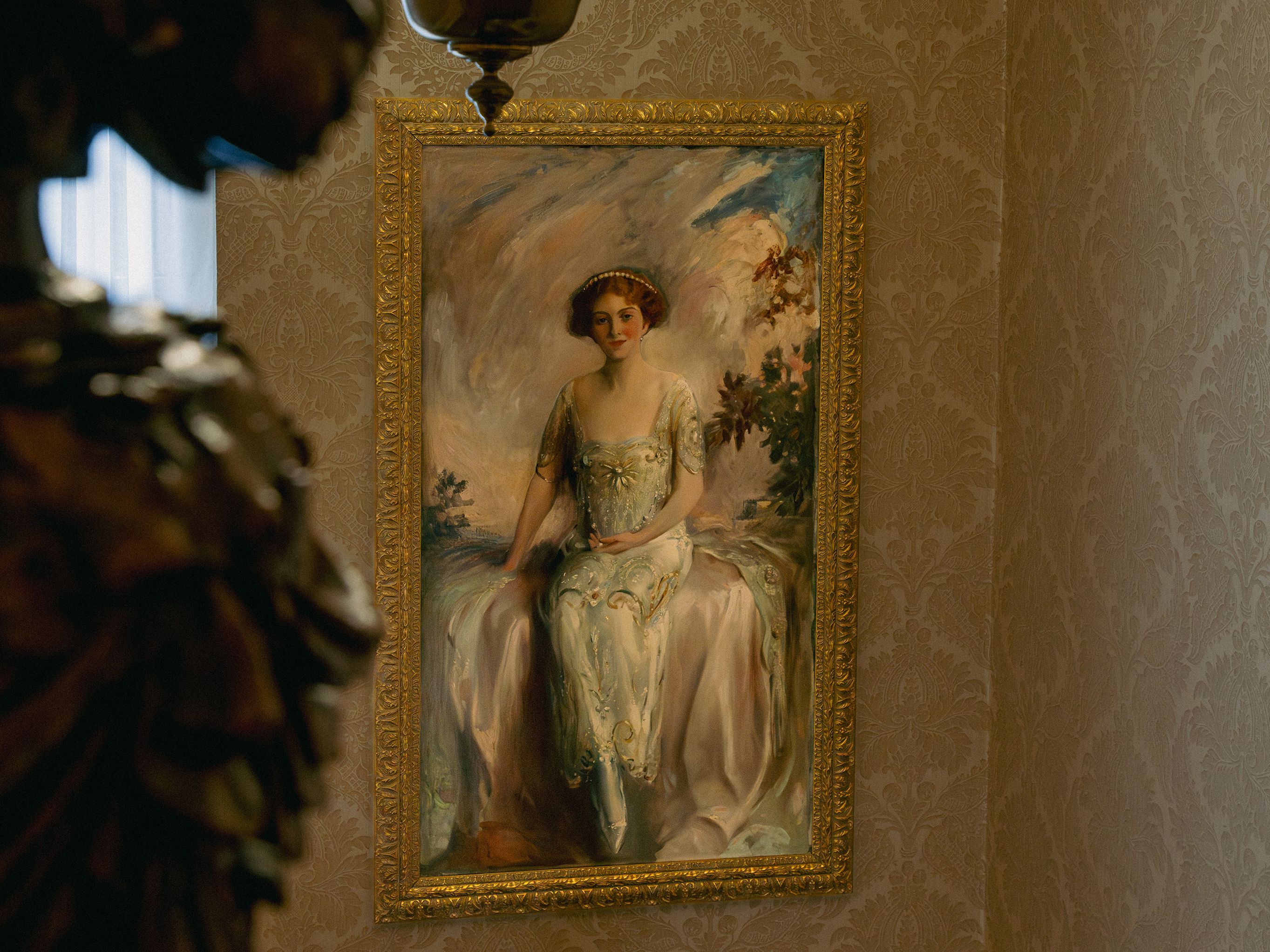 Elegant chandelier and framed portrait of a seated woman in a classical interior