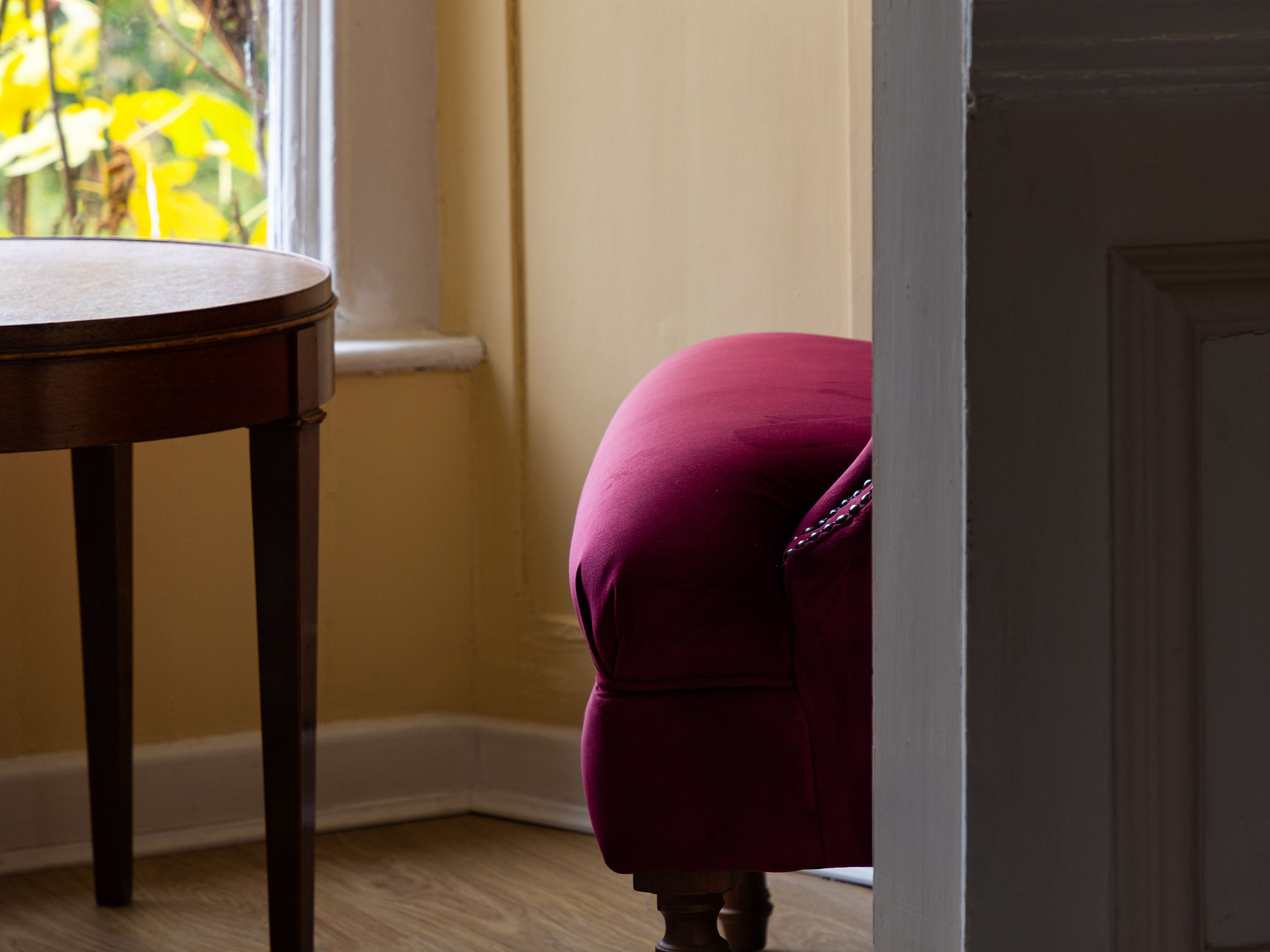 Interior scene with partial view of a red armchair and small wooden table near a window