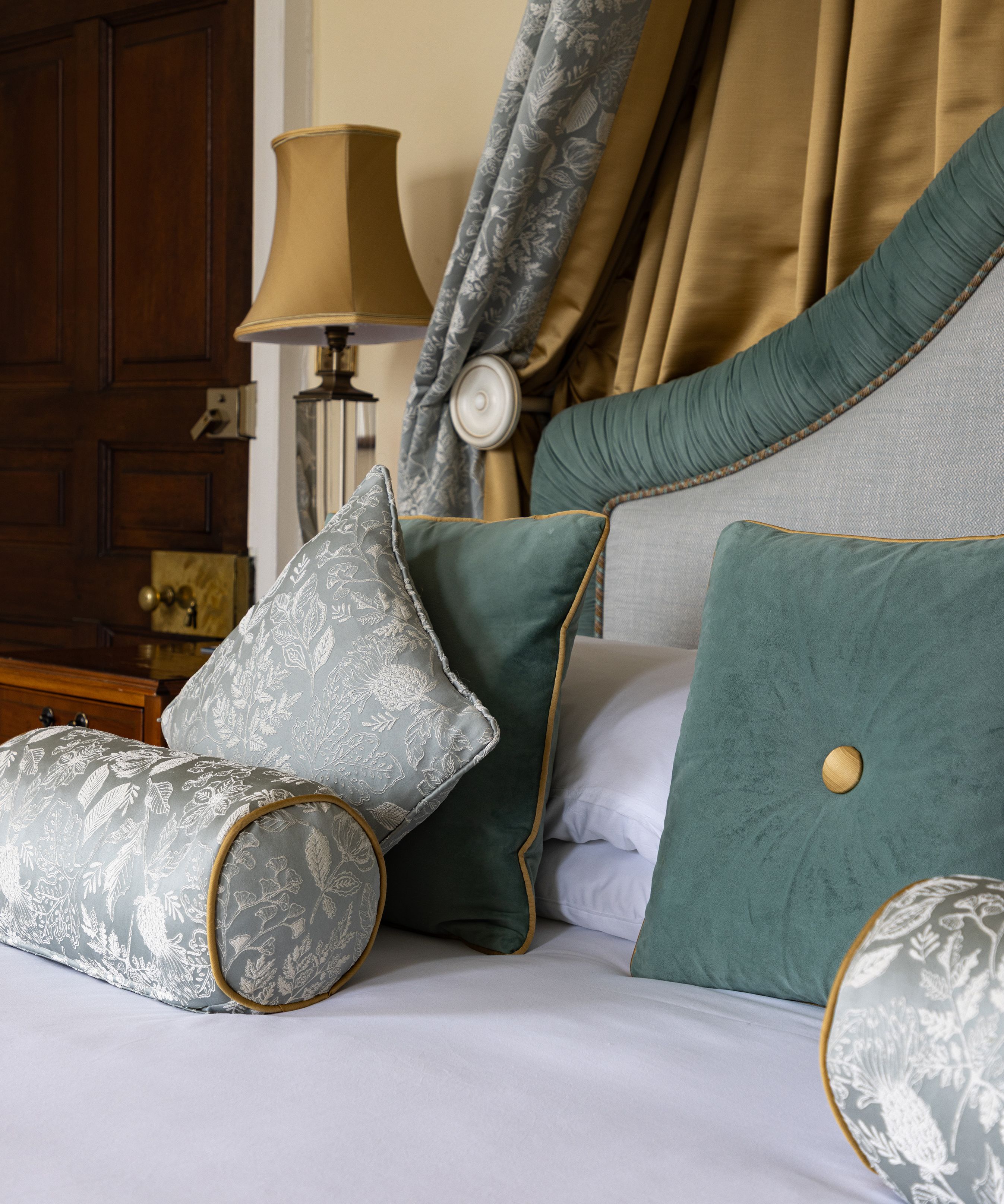 Luxury bed with velvet and patterned pillows in an elegantly decorated room